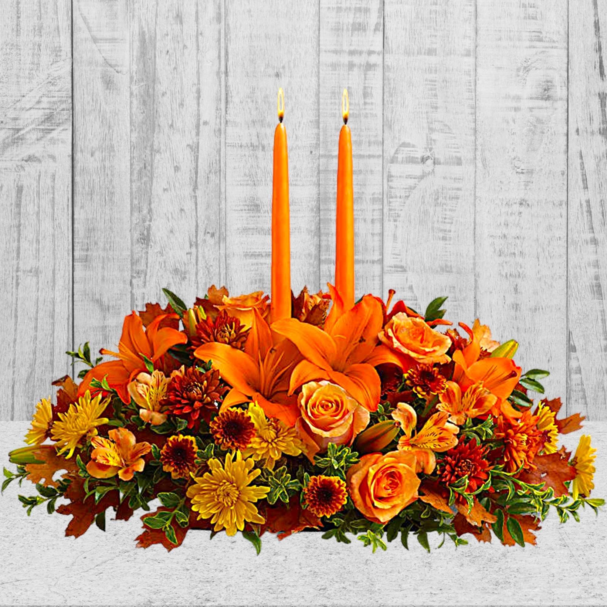 Orange floral centerpiece with two tall candles
