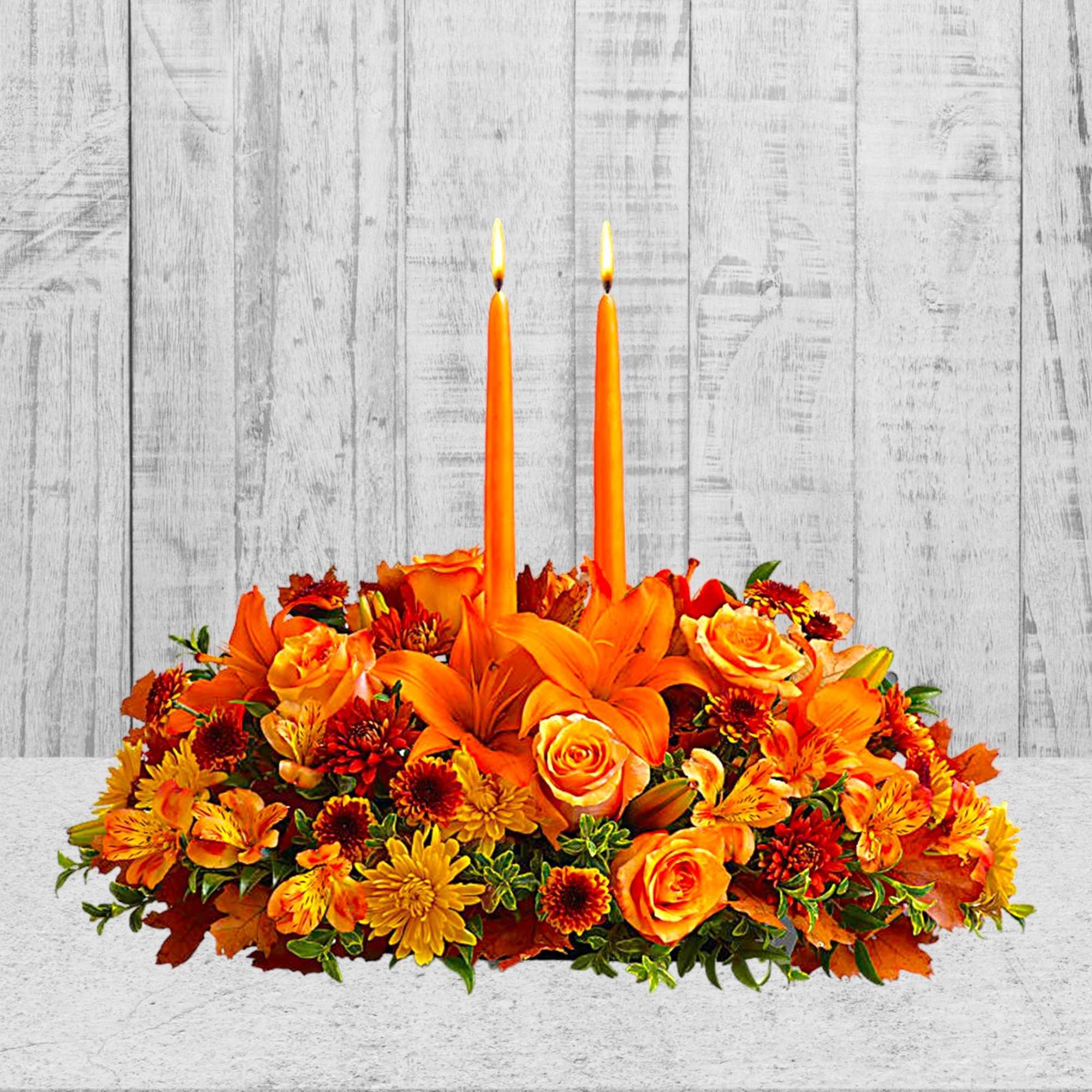 Orange floral centerpiece with two lit taper candles, photo 5 of 5