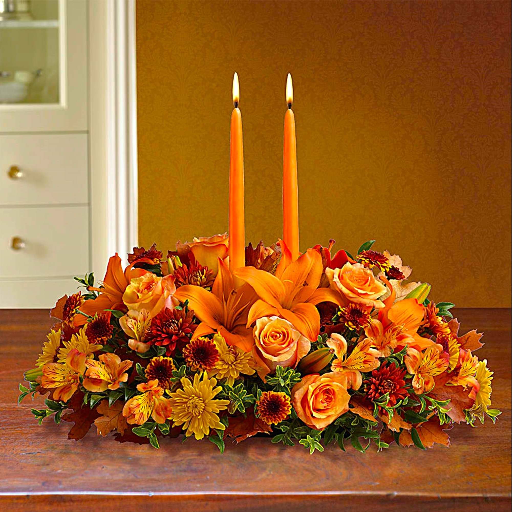Orange floral centerpiece with two lit taper candles, photo 3 of 5