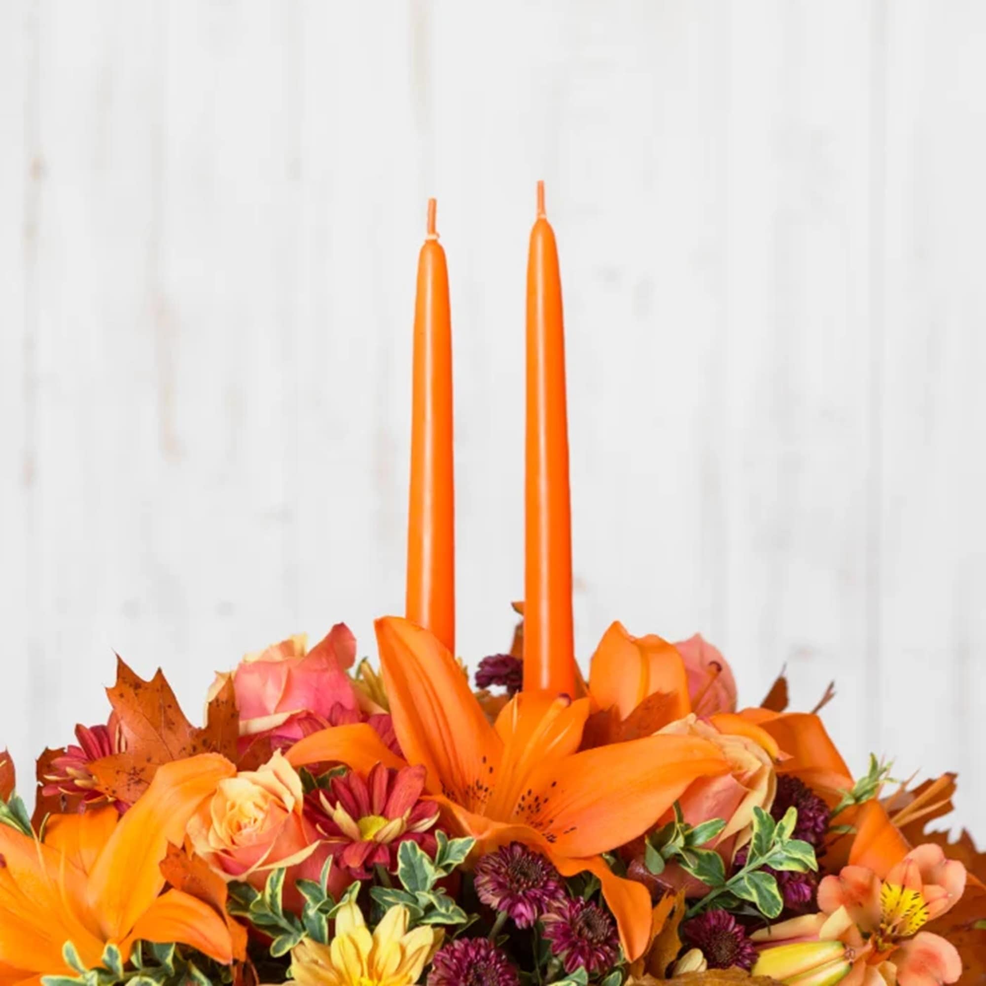 Orange floral centerpiece with two tall orange candles