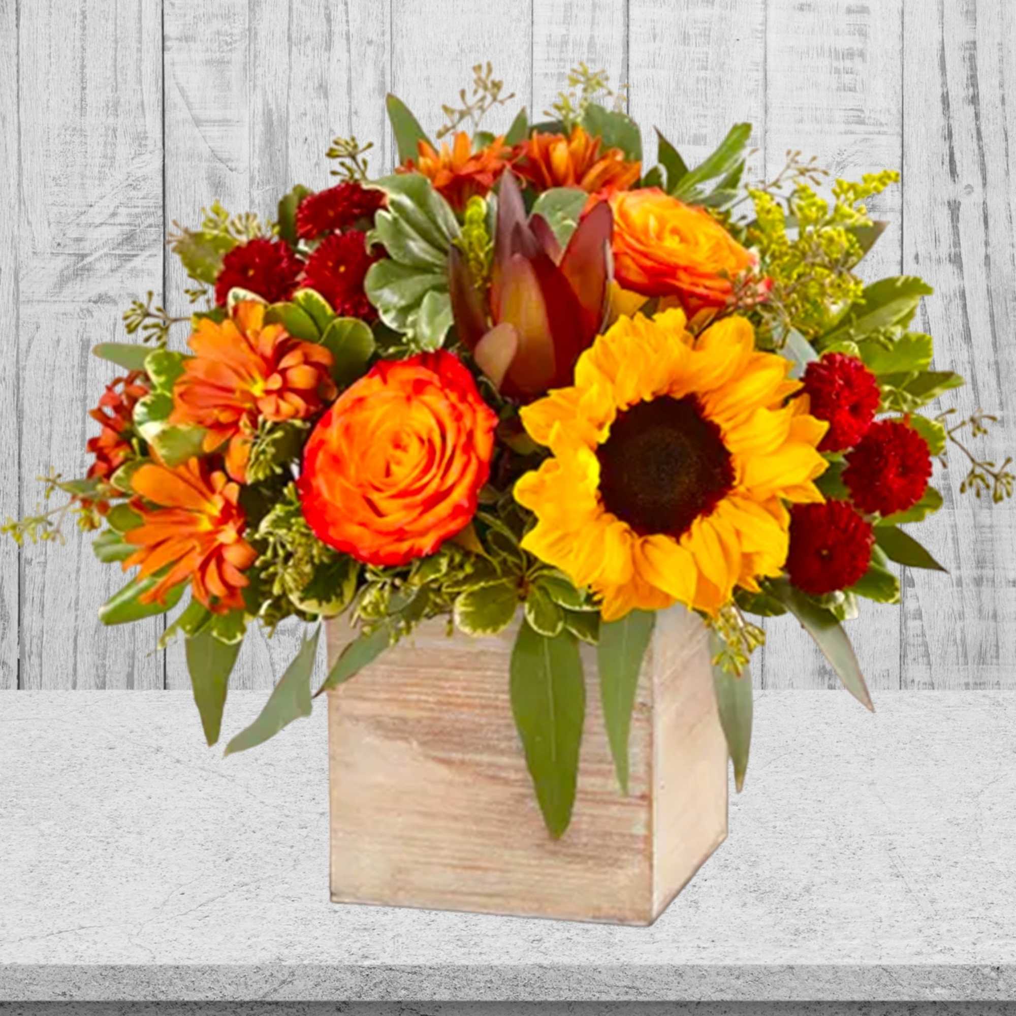 Orange and yellow floral arrangement in a wooden box