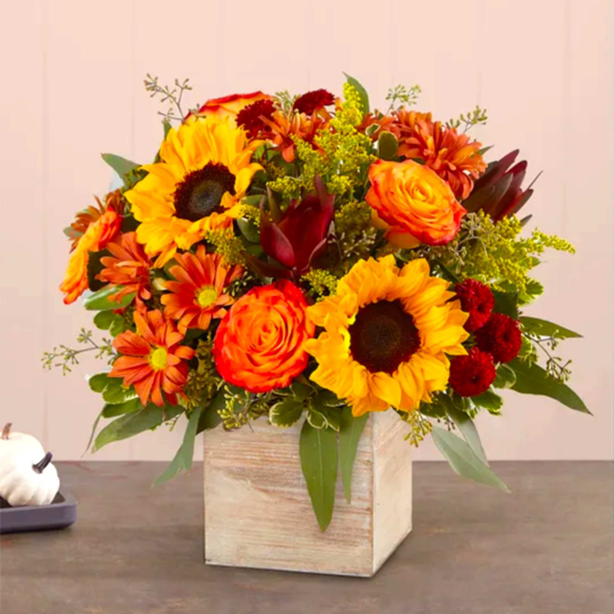Orange and yellow floral arrangement in a wooden cube vase