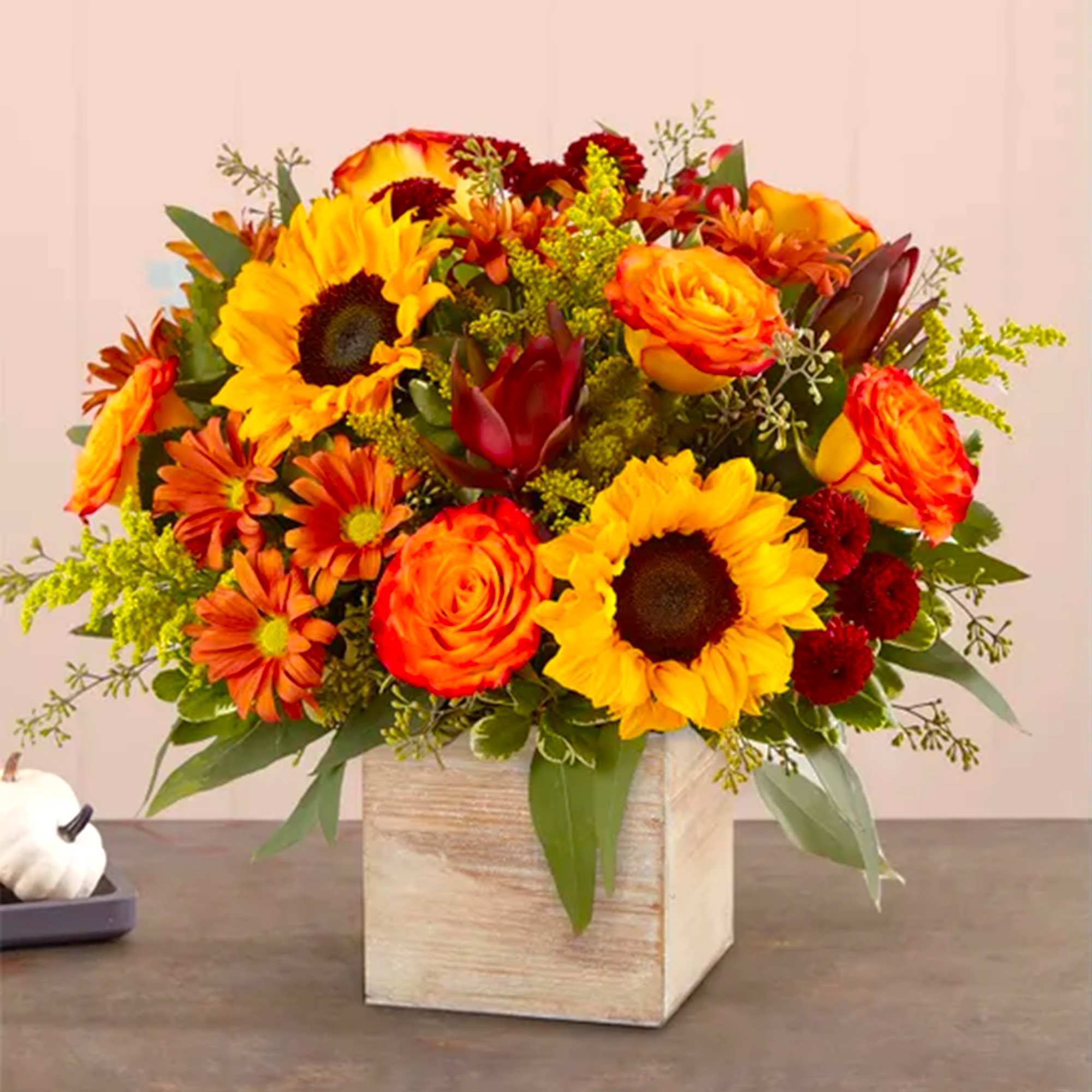 Orange and yellow mixed flower arrangement in a wooden cube vase