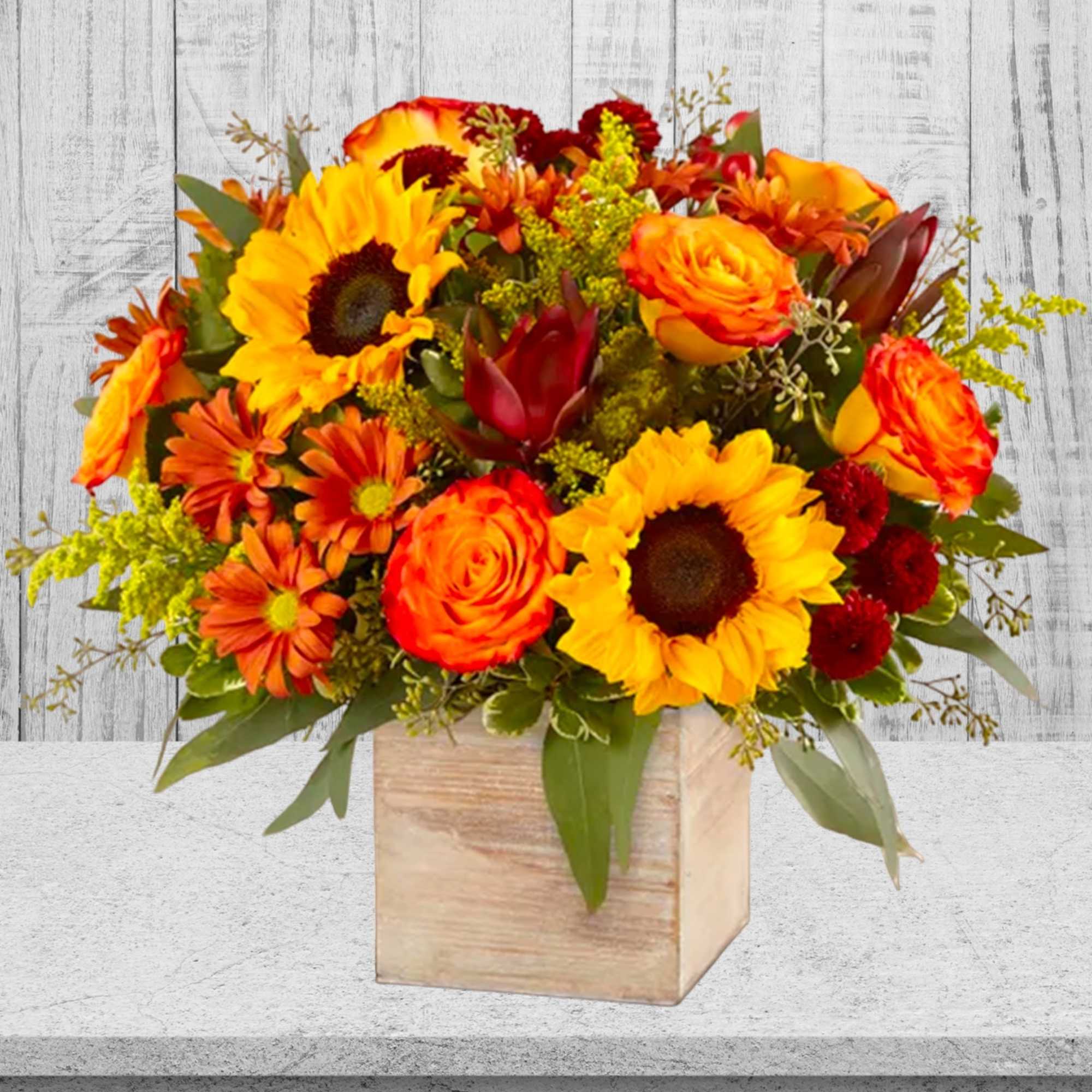 Bright orange and yellow bouquet in a wooden cube vase