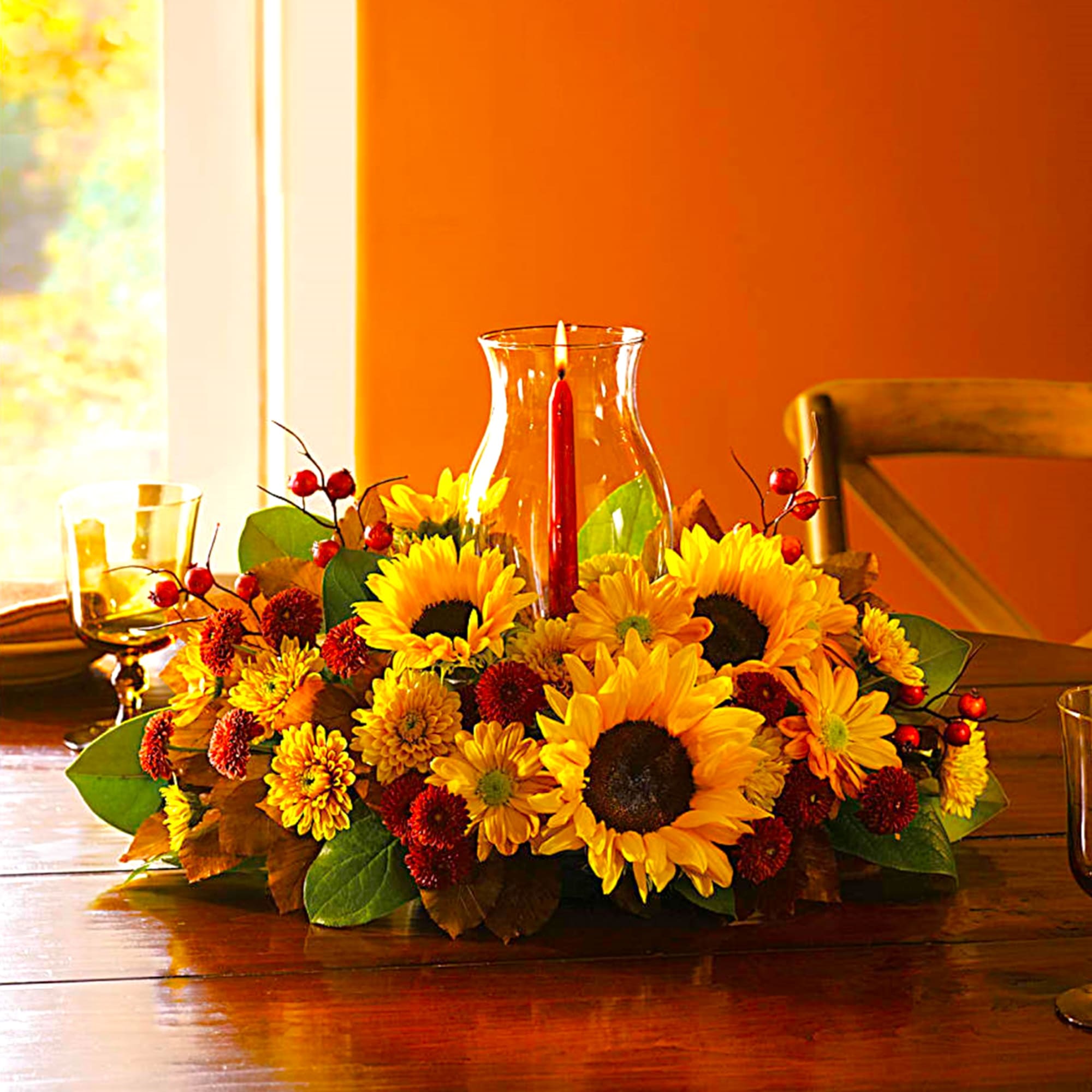 Sunflower centerpiece with red berries and a glass candle holder