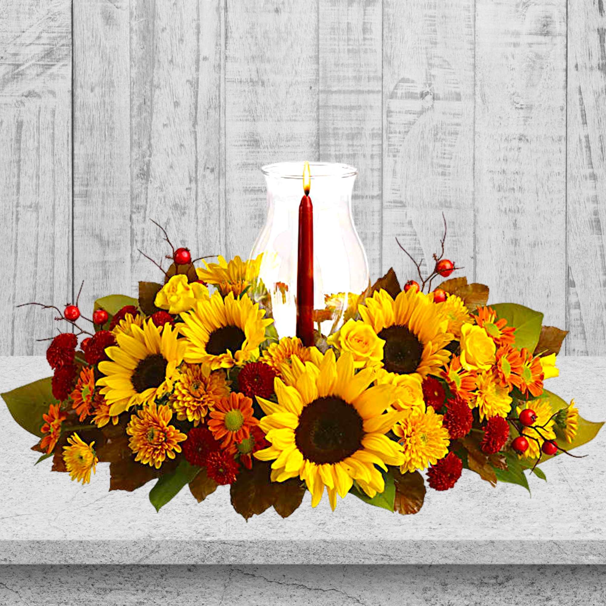 Sunflower and autumn flower centerpiece with a lit candle in a glass hurricane