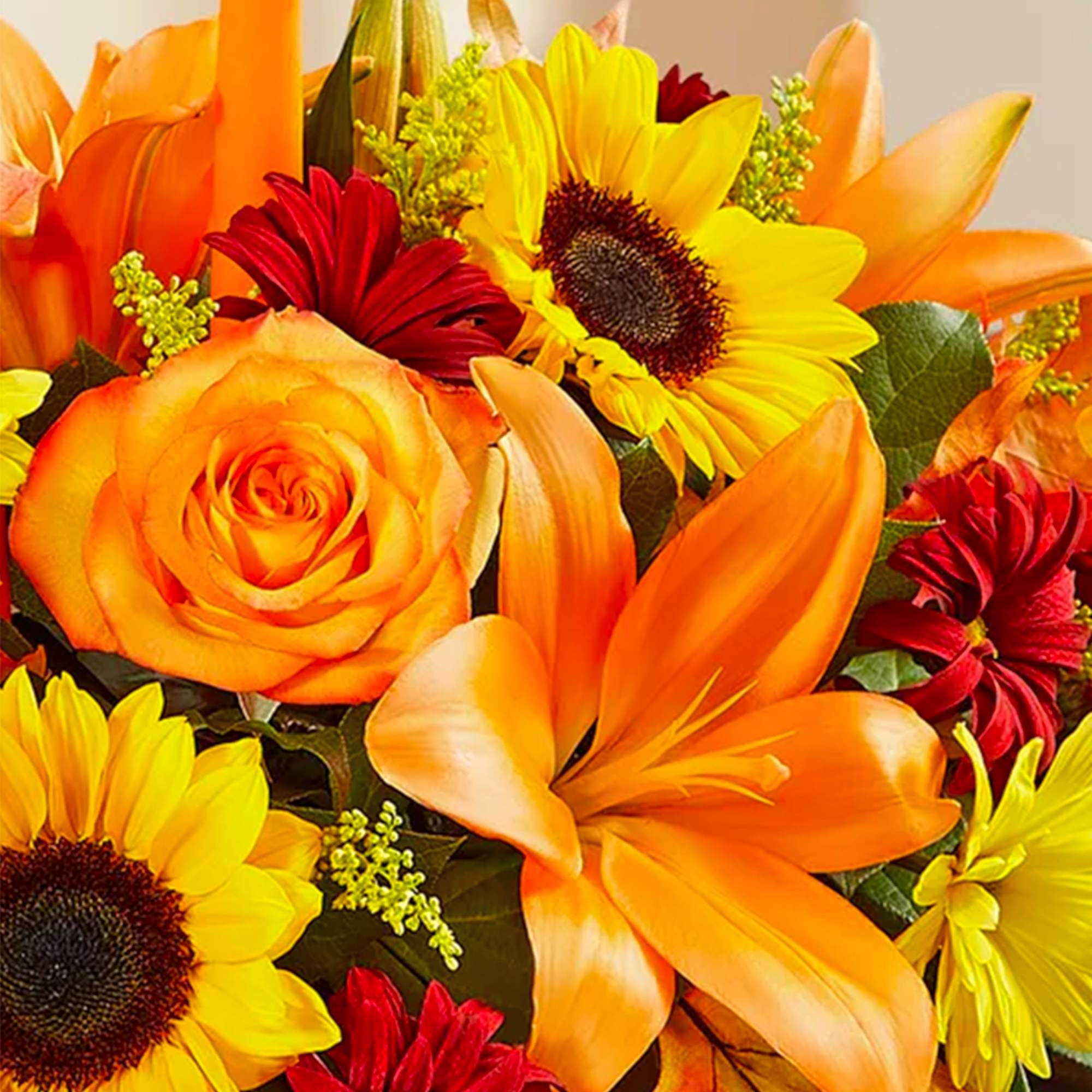 Orange roses, lilies, sunflowers, and red daisies in a bright bouquet