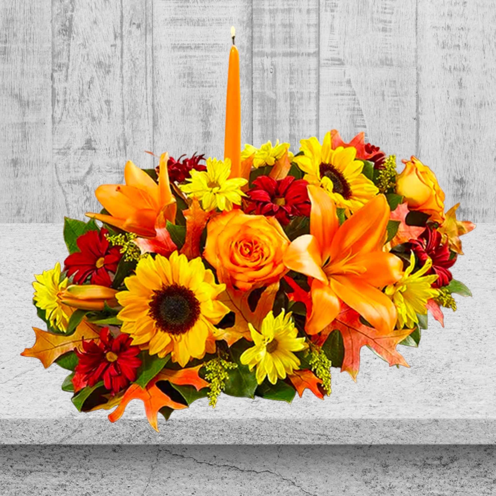 Autumn floral centerpiece with orange lilies, sunflowers, and a candle