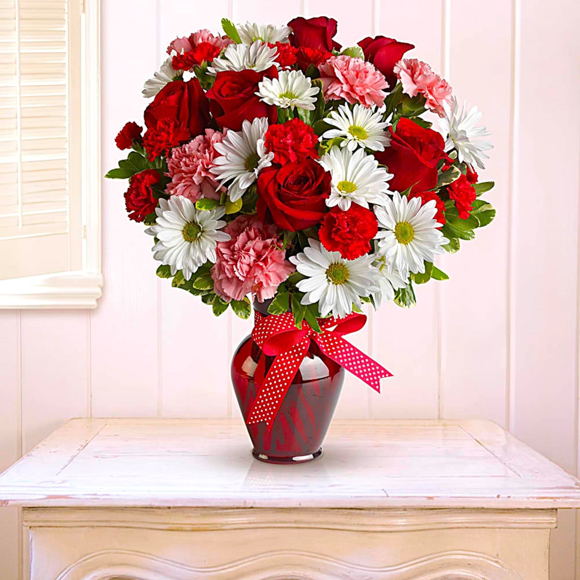 Bouquet of red roses, white daisies, and pink carnations in a red vase, photo 2 of 5