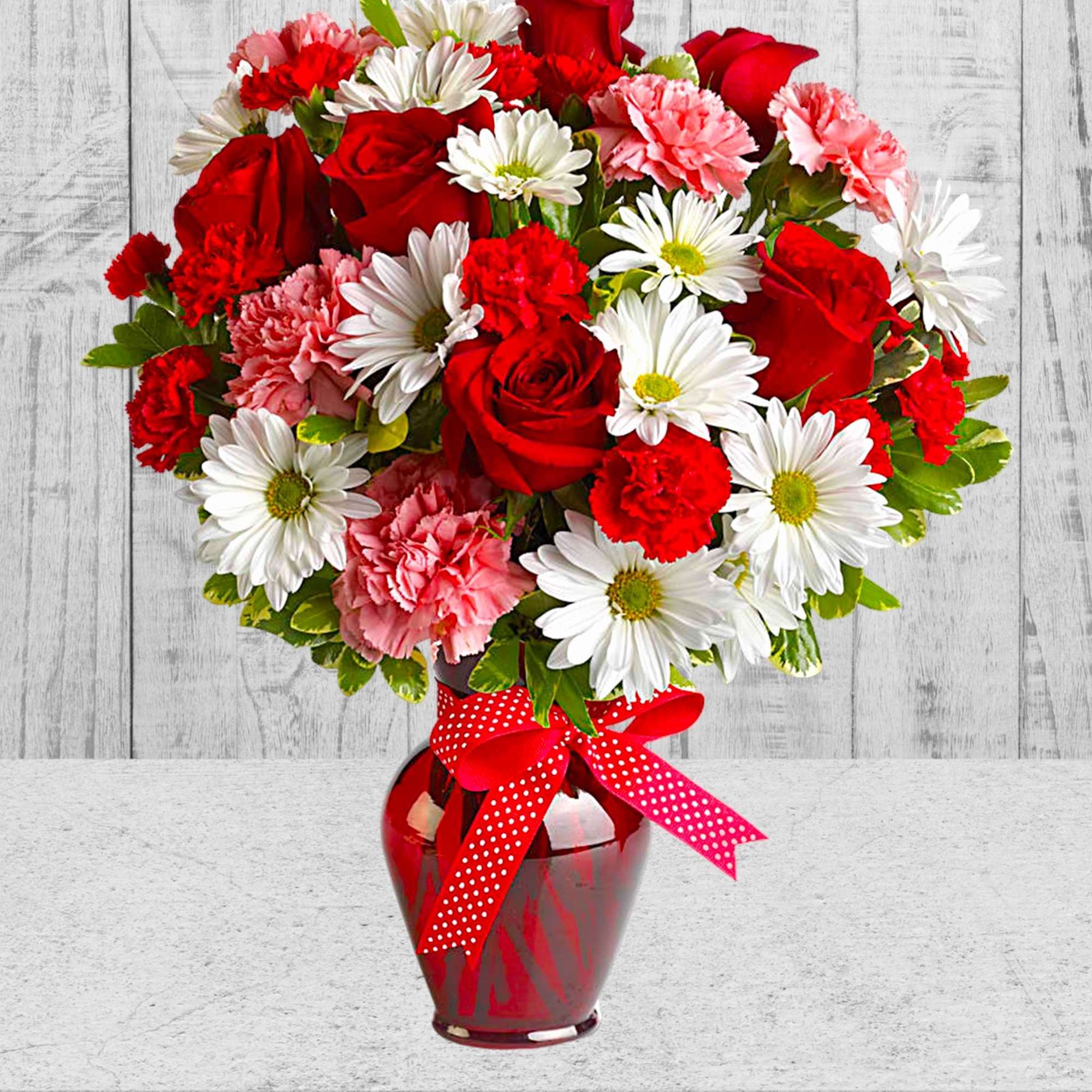 Red roses, white daisies, and pink carnations in a red vase with a polka-dot ribbon, photo 3 of 5