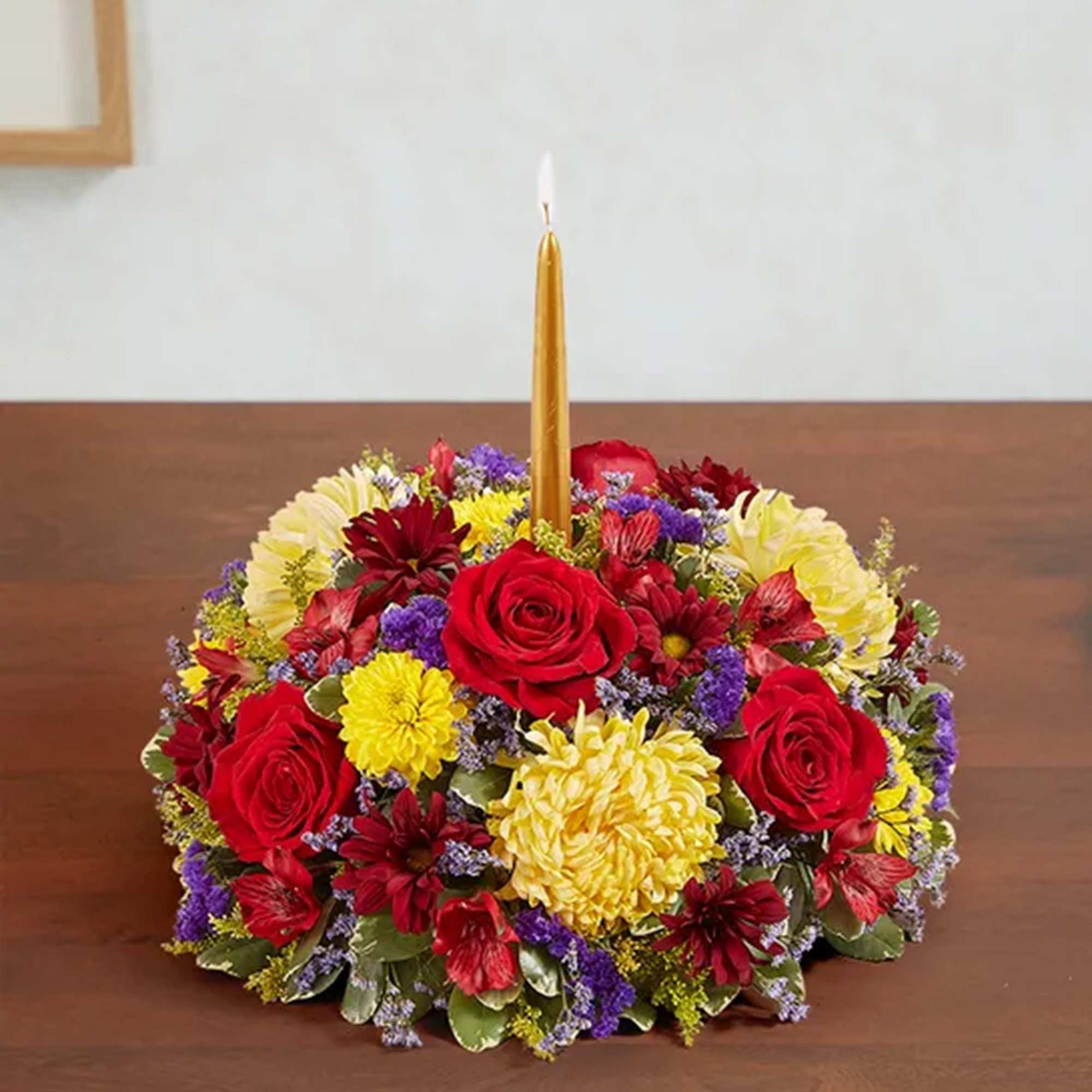Round floral centerpiece with a gold taper candle in the middle