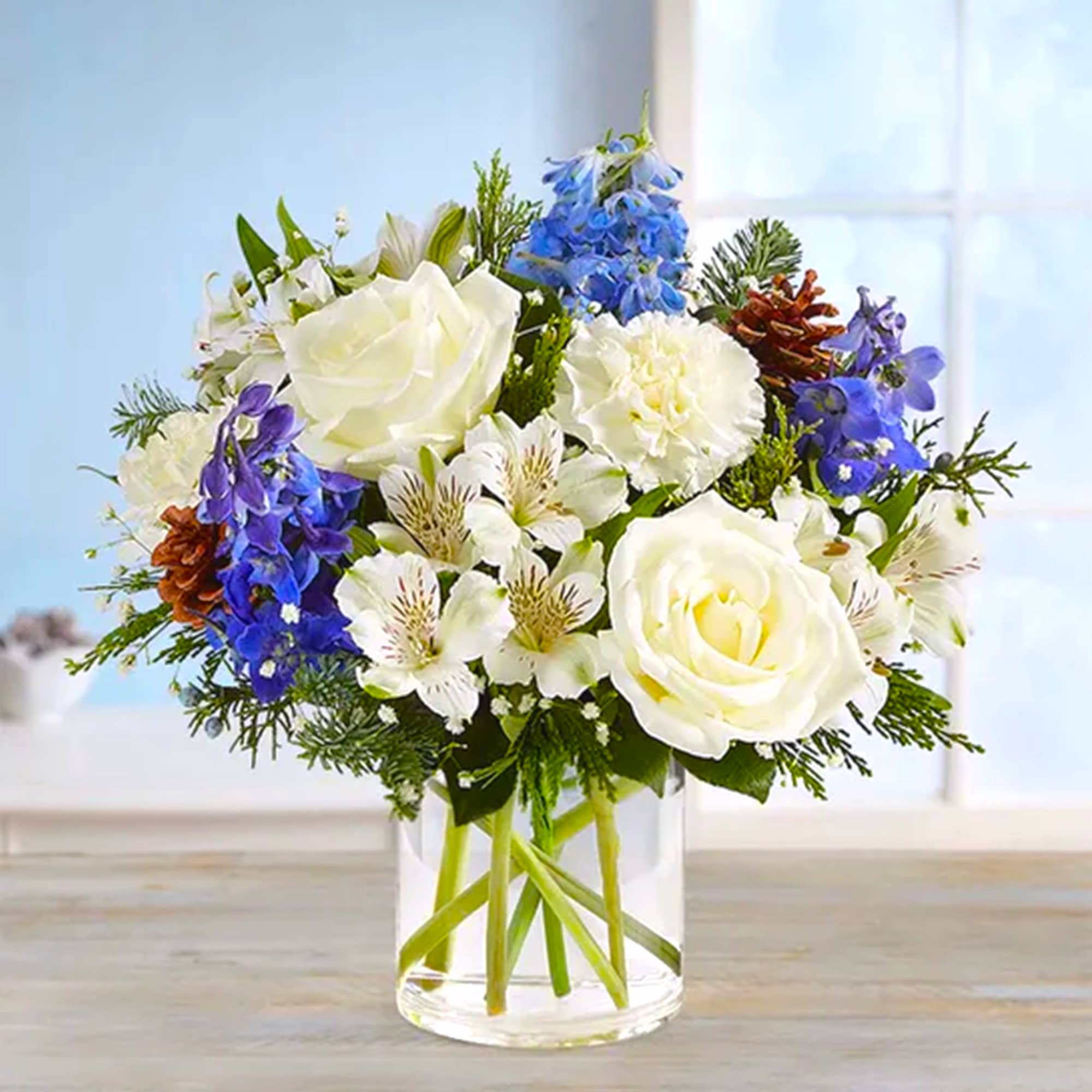 White and blue mixed bouquet in a clear glass vase