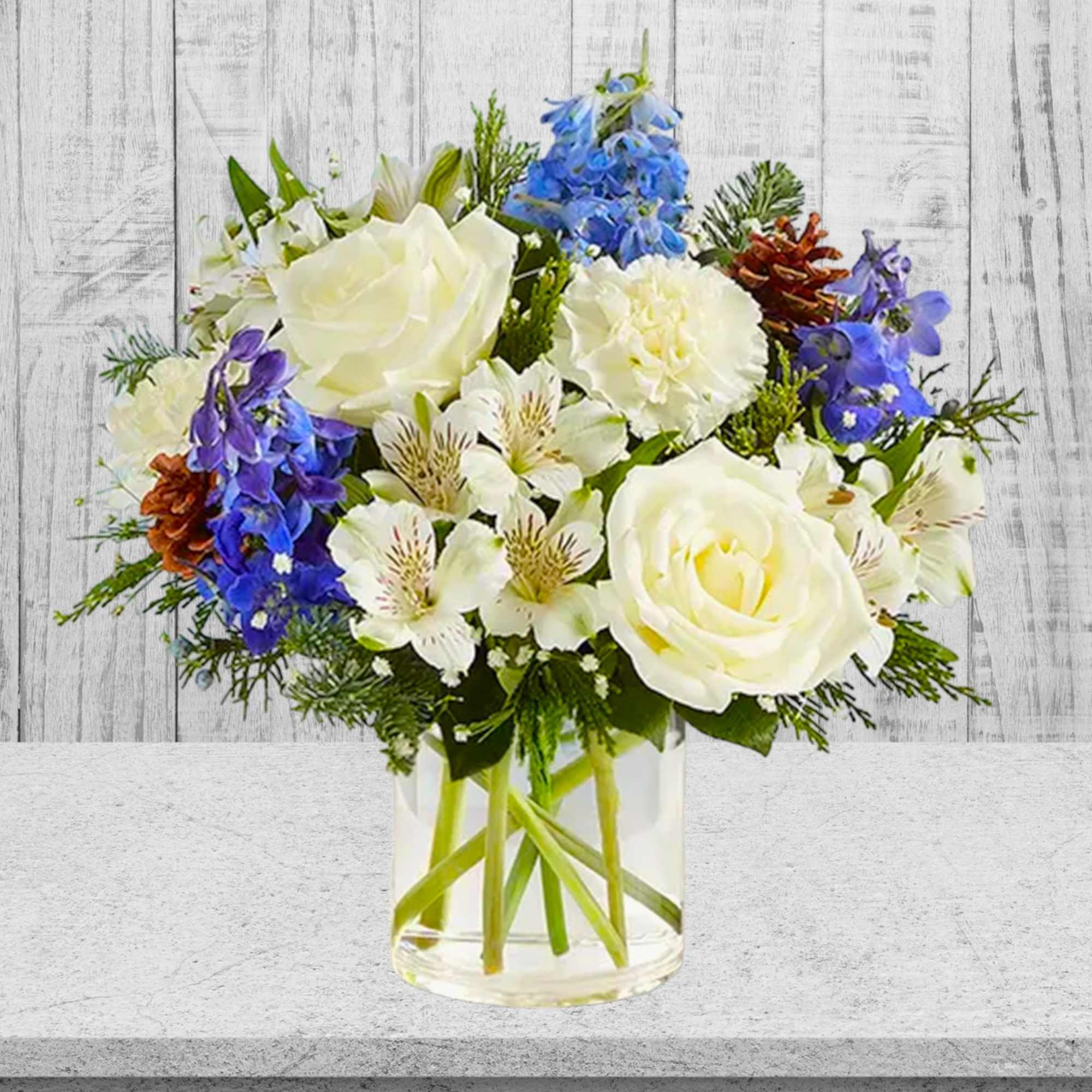 White roses and blue flowers in a clear glass vase