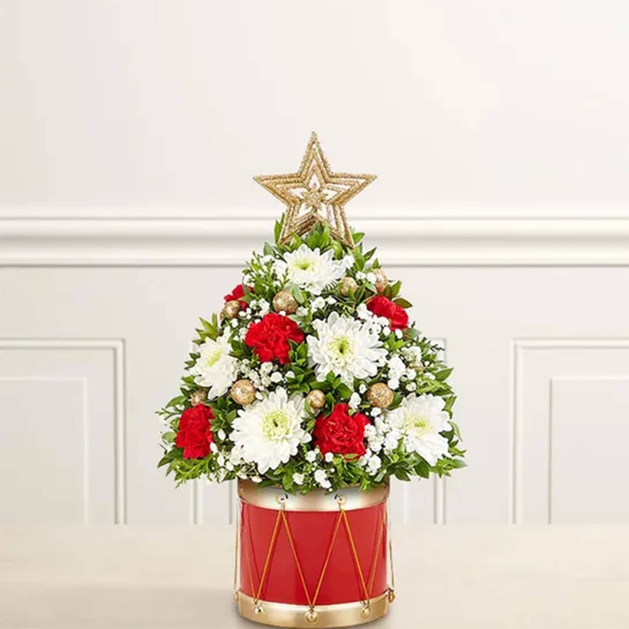 Christmas tree-shaped floral arrangement in a red drum container with a star topper