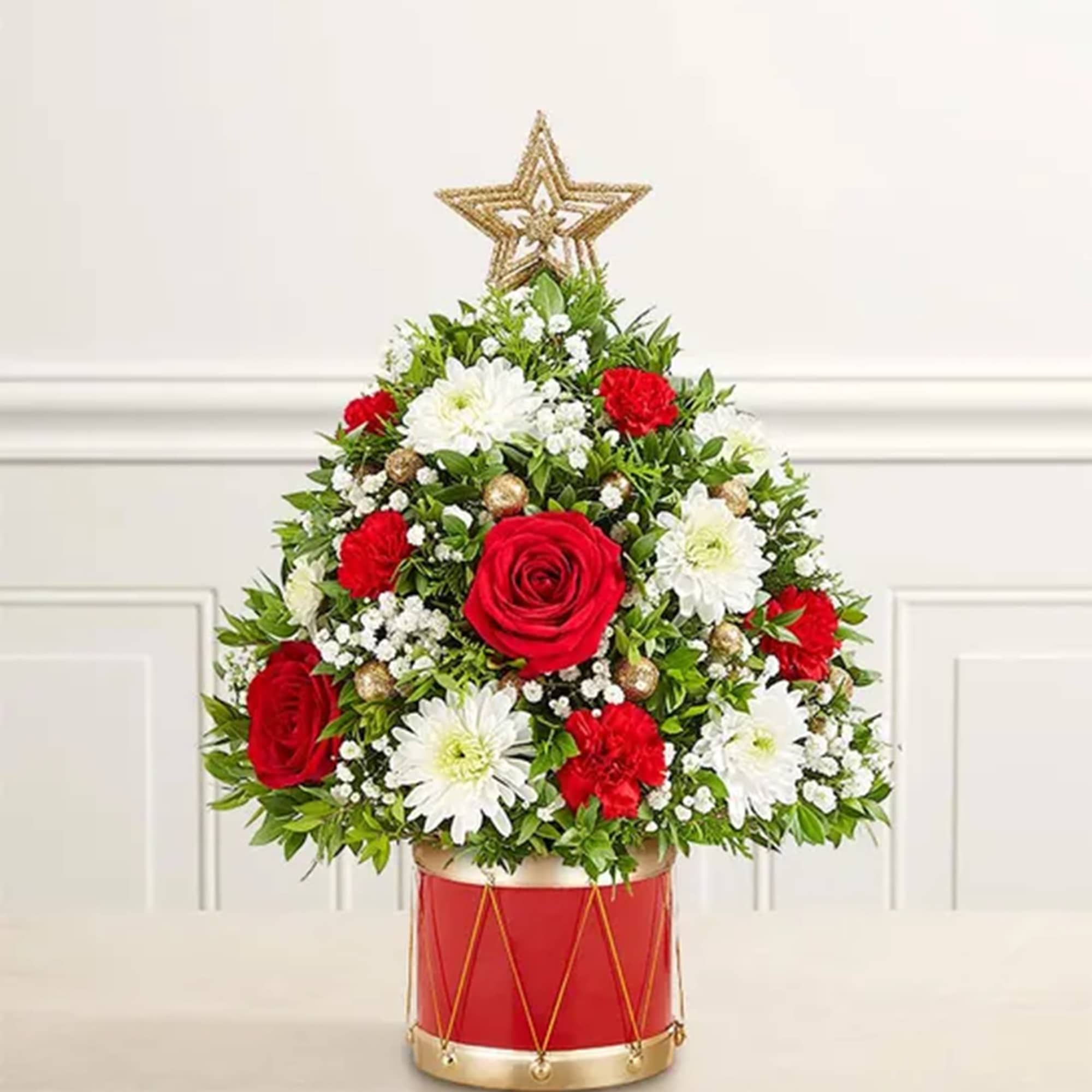 Red and white floral arrangement in a red drum container with a gold star topper