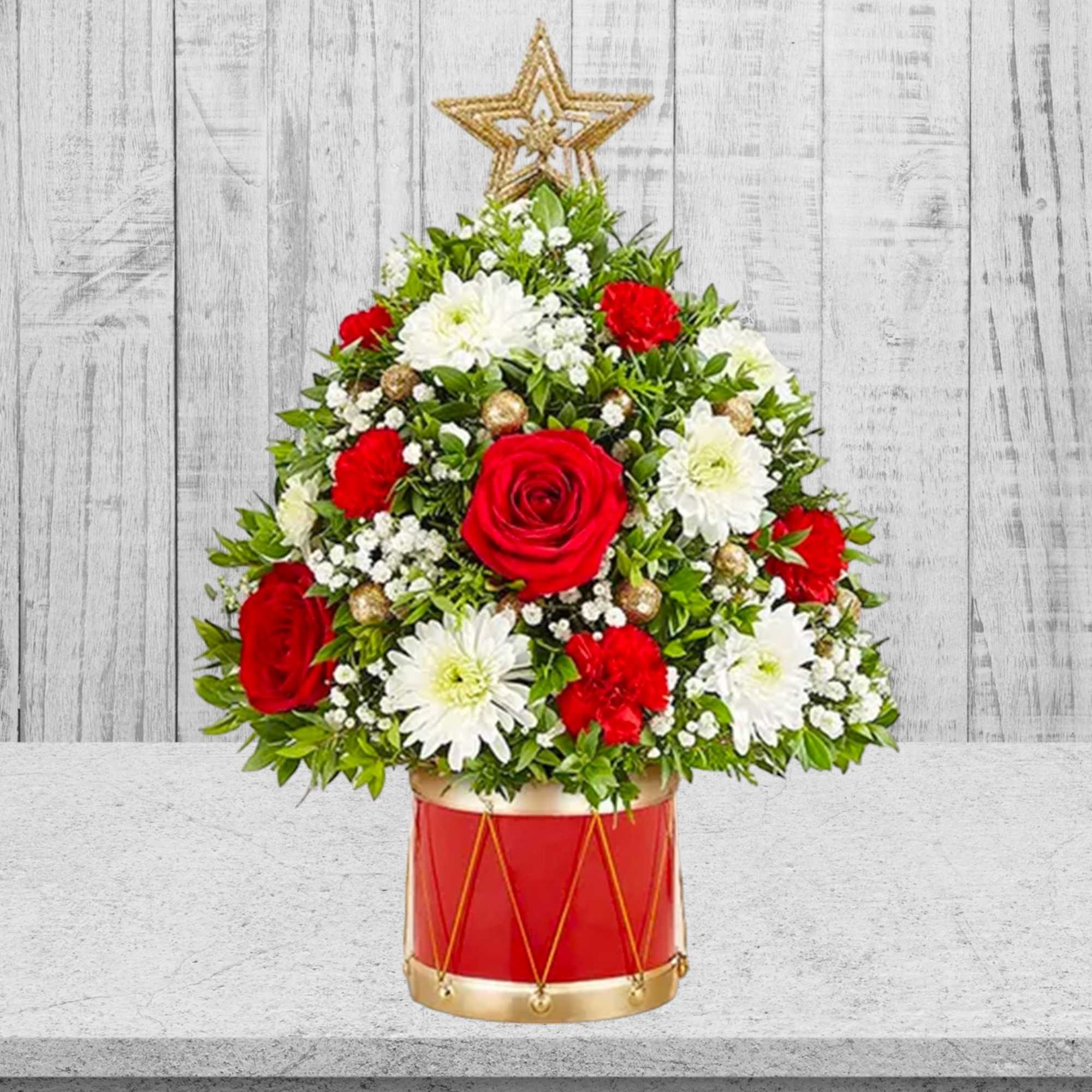 Red and white floral arrangement in a red drum container with a star topper