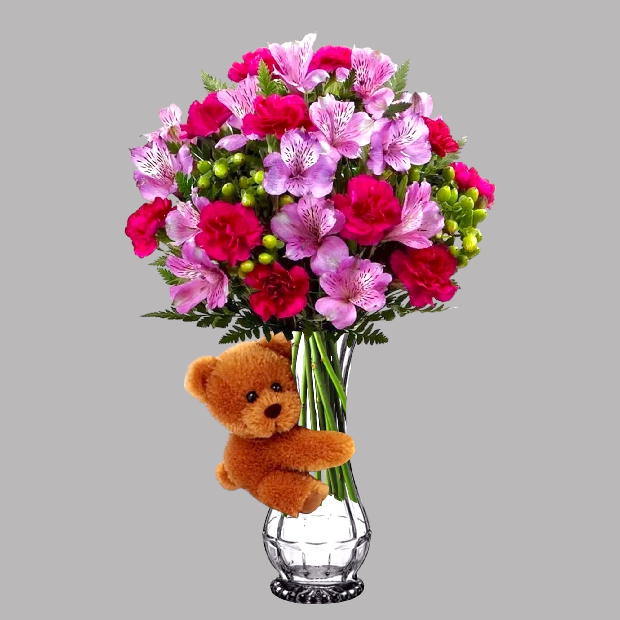 Pink and purple bouquet in a clear vase with a teddy bear attached