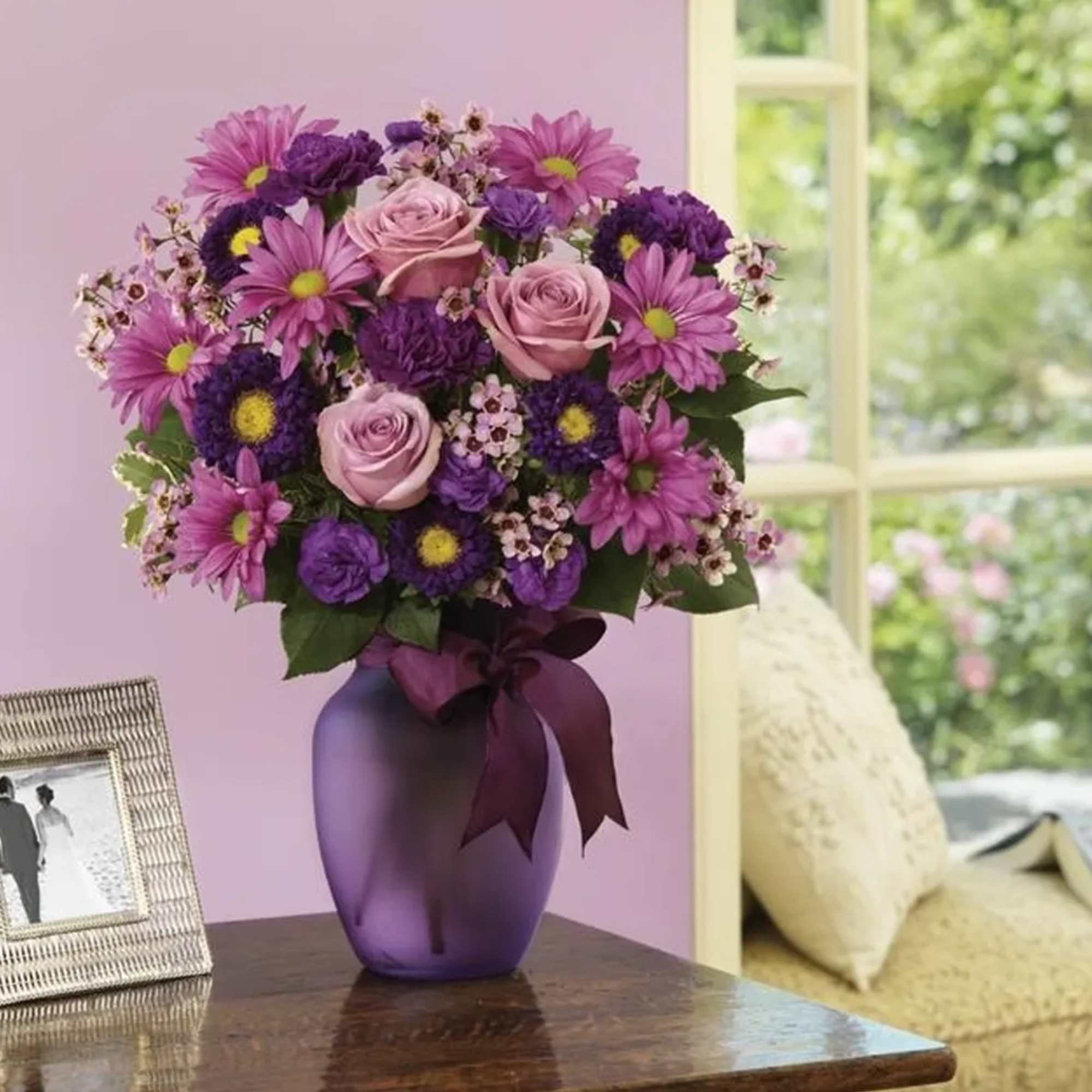 Purple and pink bouquet in a purple vase on a table