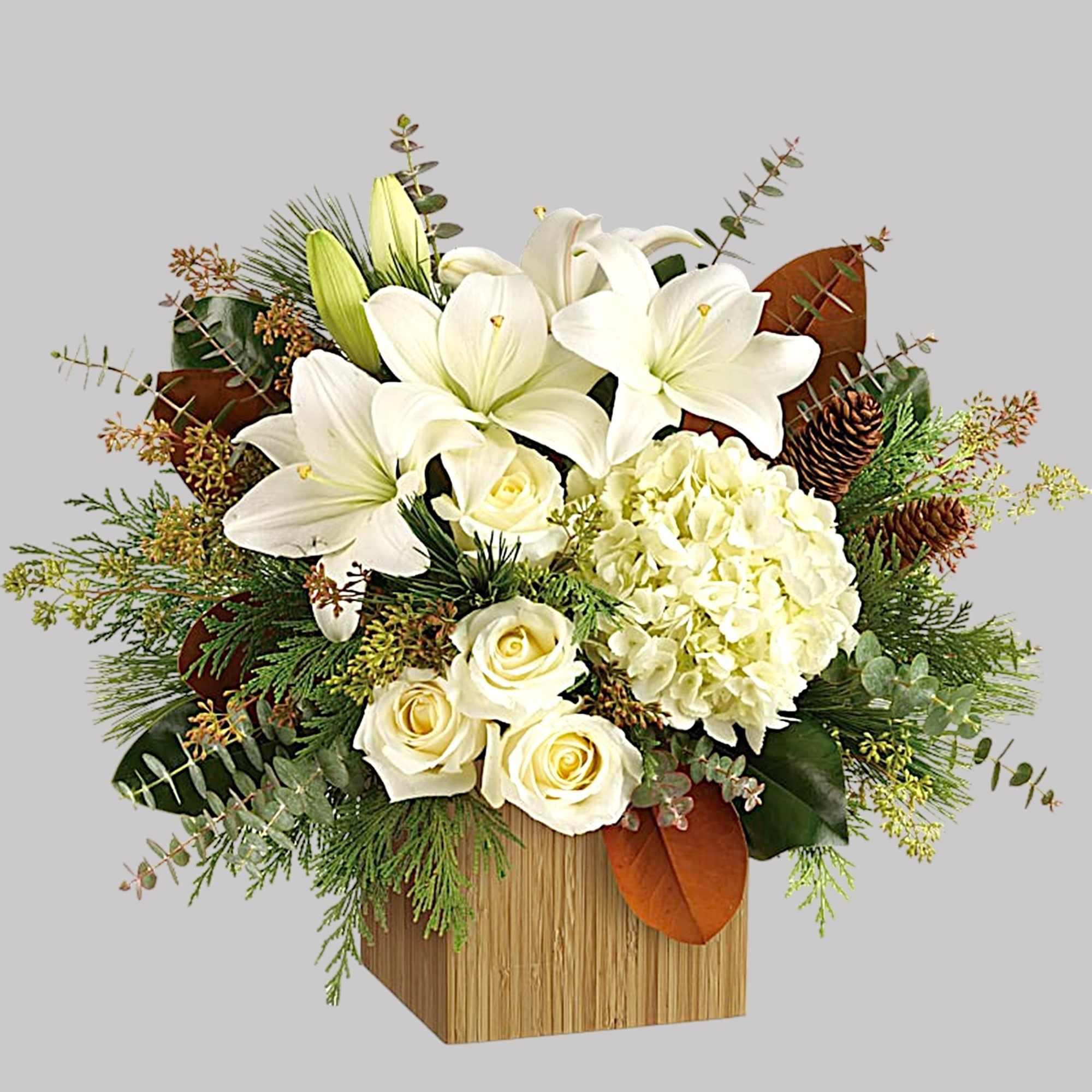 White lilies and roses arranged in a wooden box with pinecones and greenery