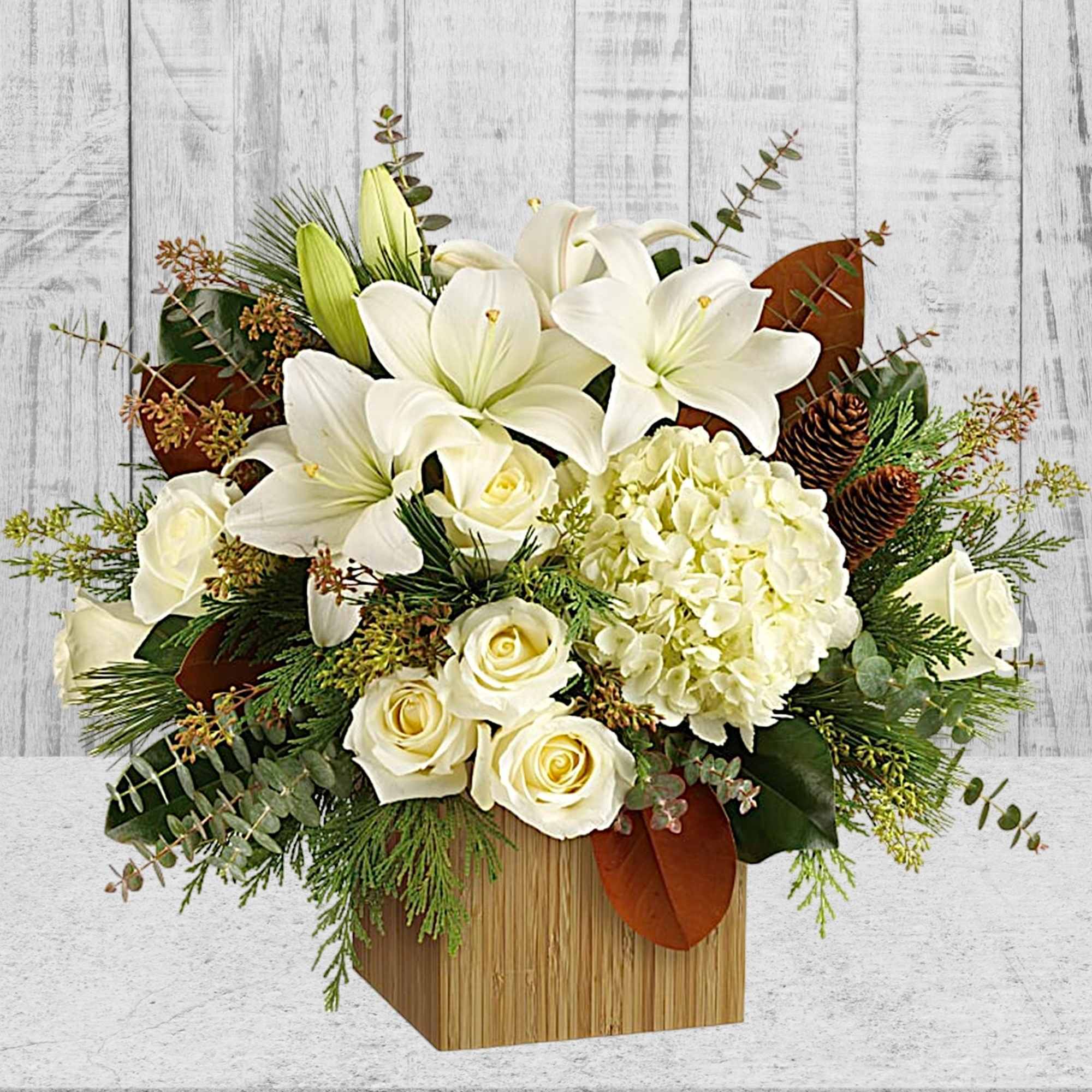 White lilies and roses arranged in a wooden box