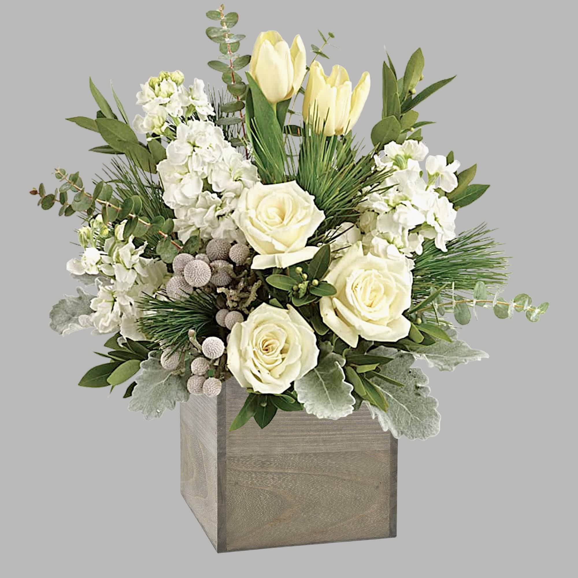 White roses and pale yellow tulips in a wooden box with greenery