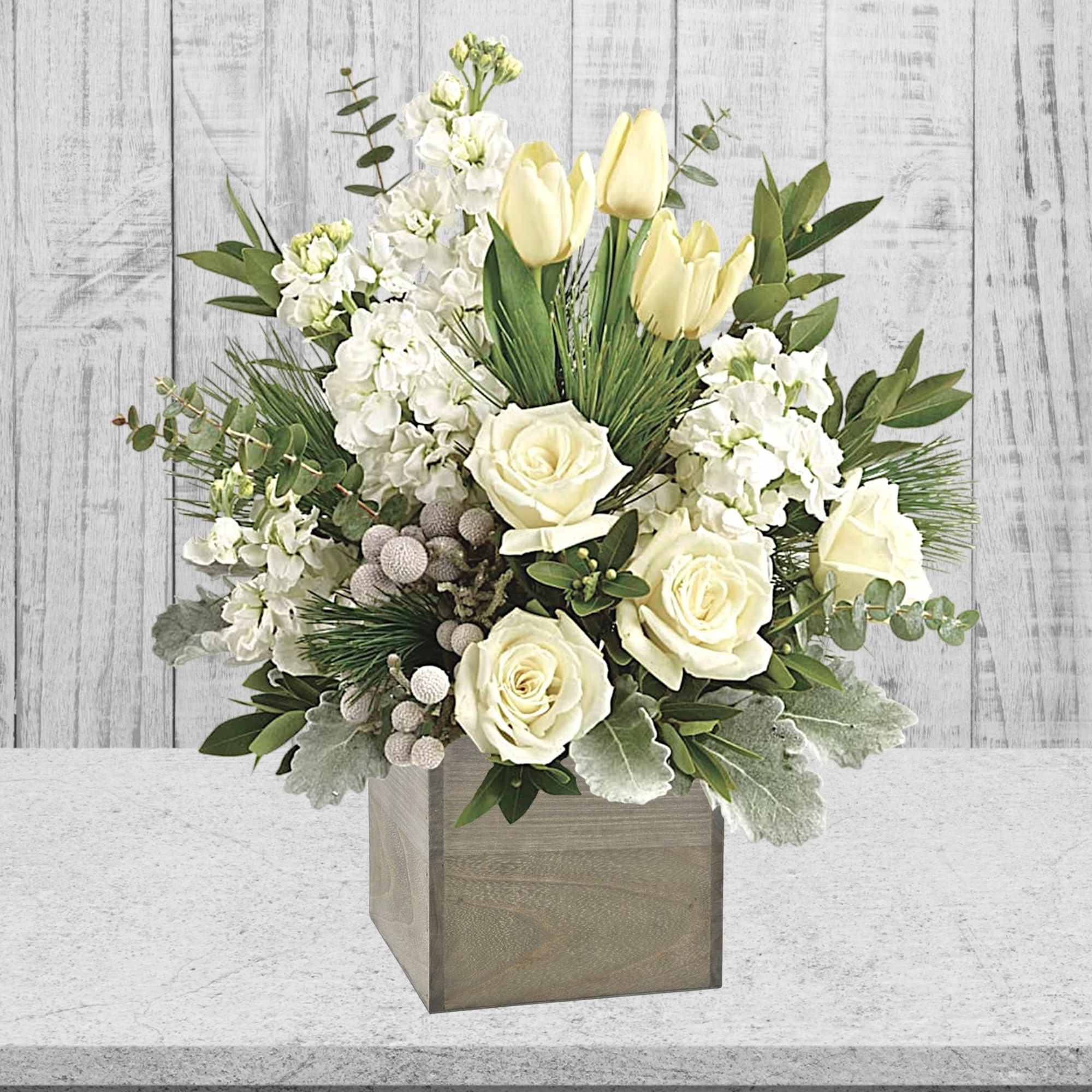 White roses and pale yellow tulips in a square wooden vase