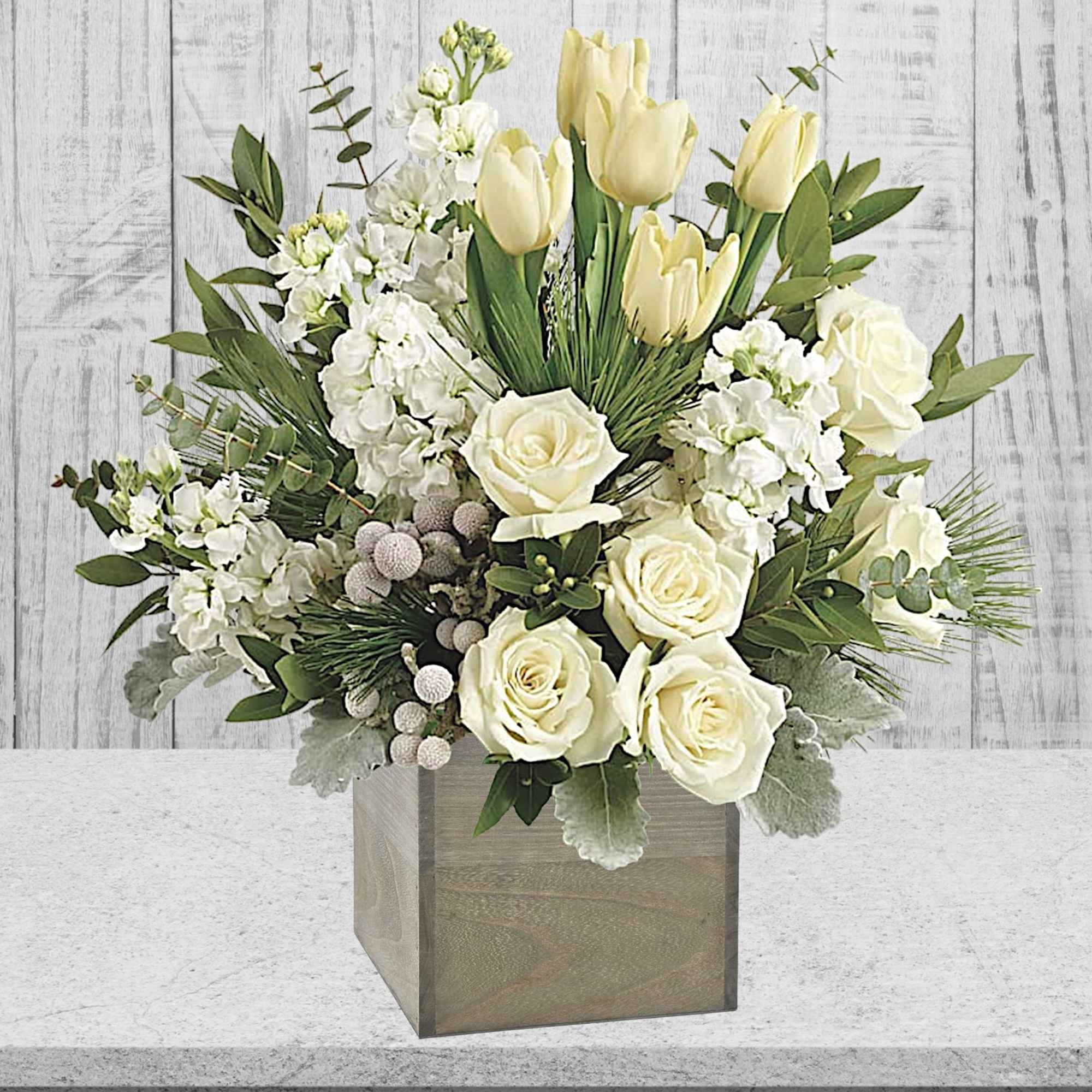 White roses and pale yellow tulips in a square wooden vase