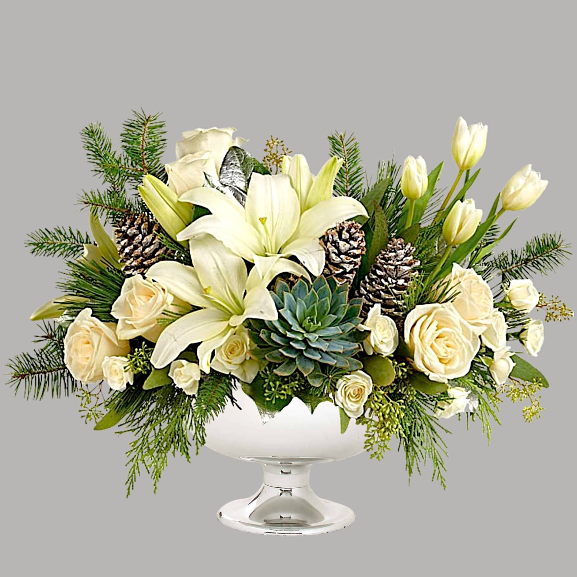 White lilies and roses arranged in a pedestal vase with pinecones and succulents