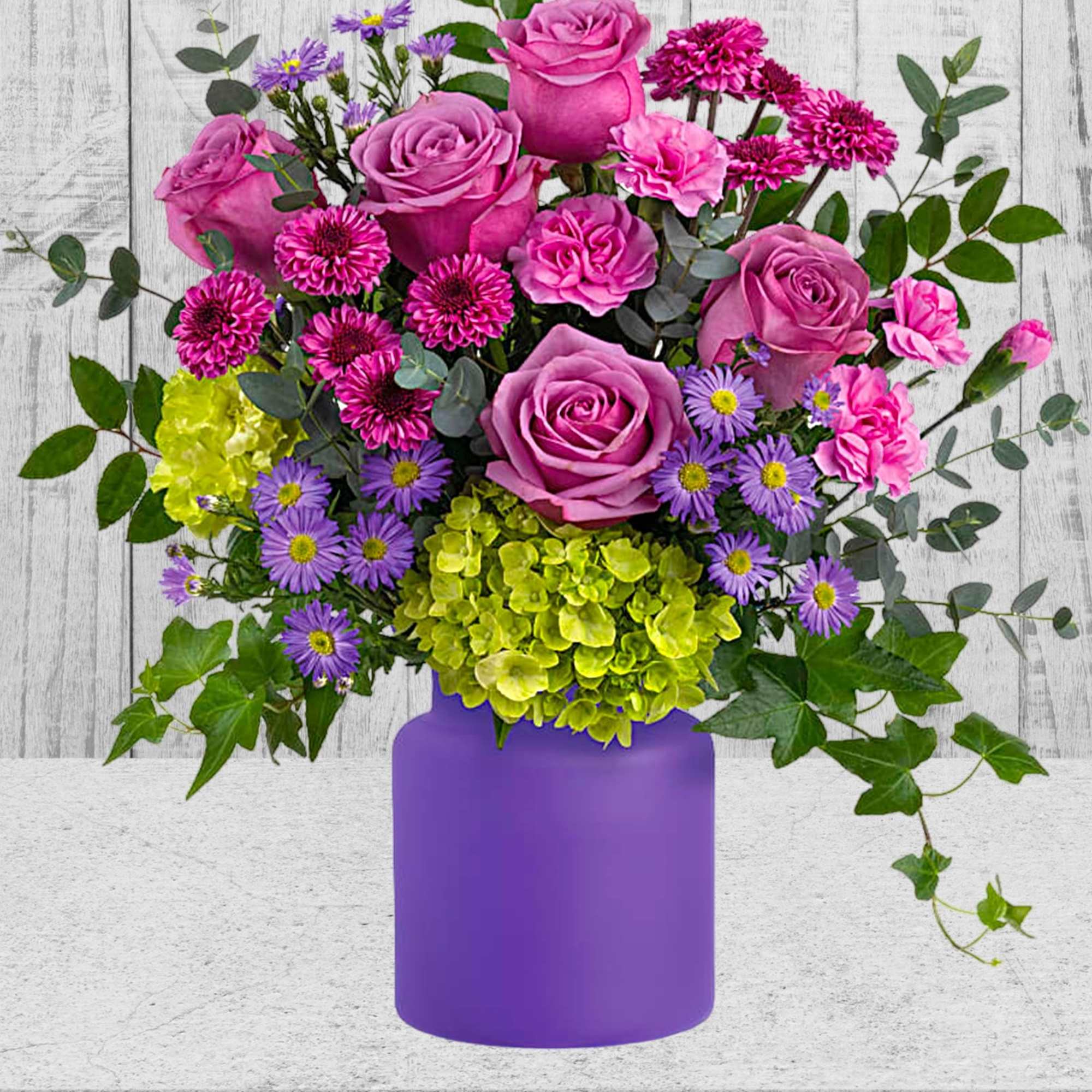 Pink roses and purple flowers arranged in a purple vase