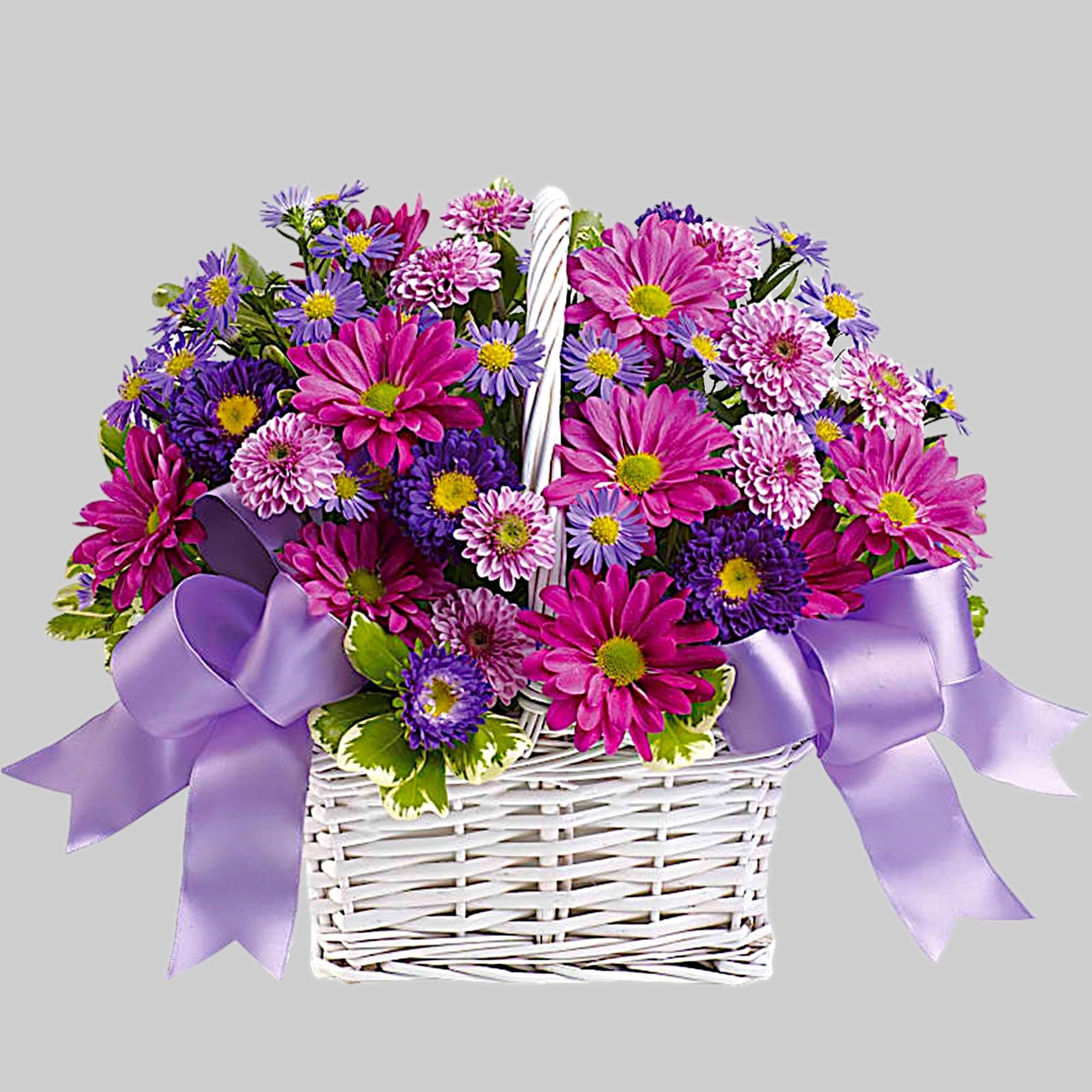 Pink and purple daisy bouquet in a white wicker basket with lavender ribbons