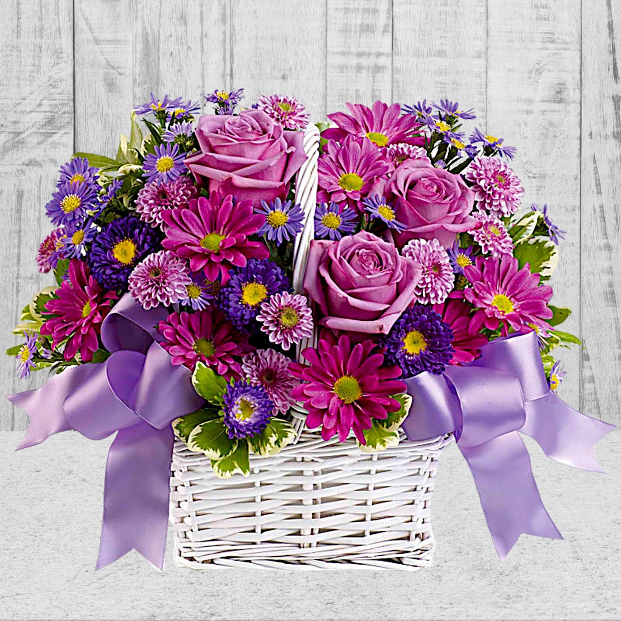 Basket of pink roses and purple daisies with lavender ribbon