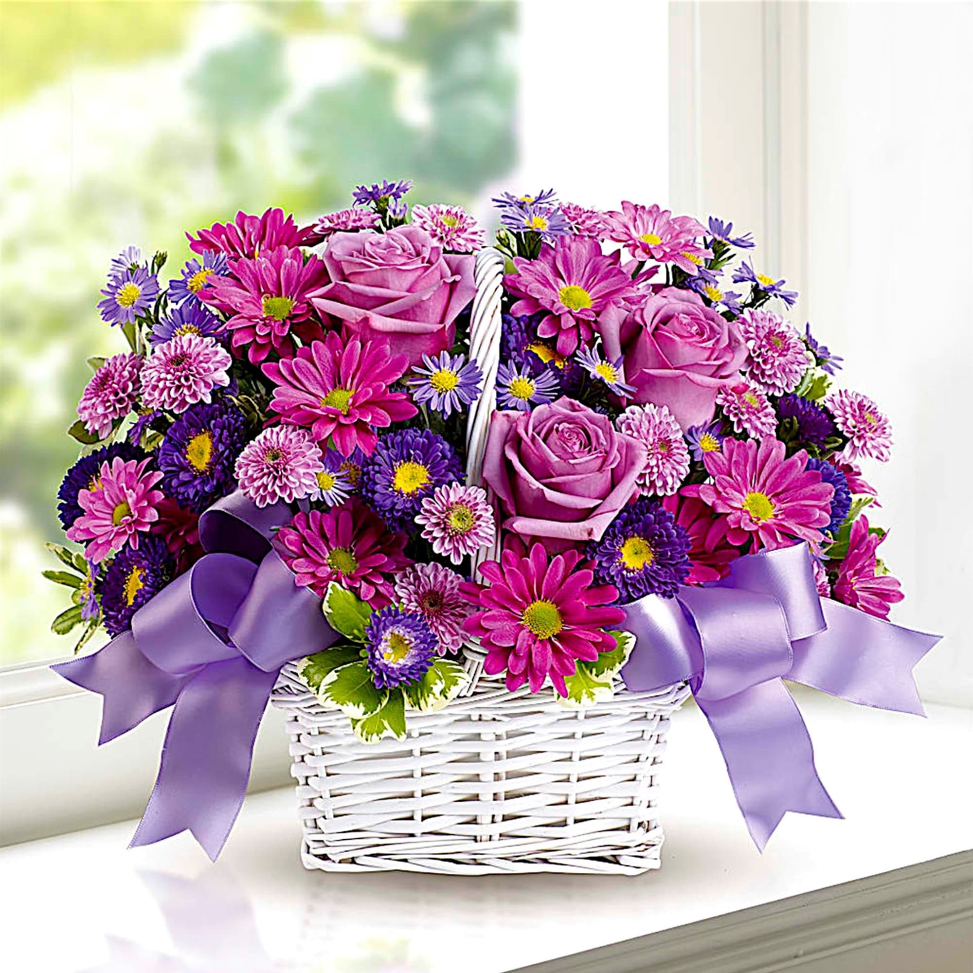 Pink and purple flower basket with roses and daisies in a white wicker basket