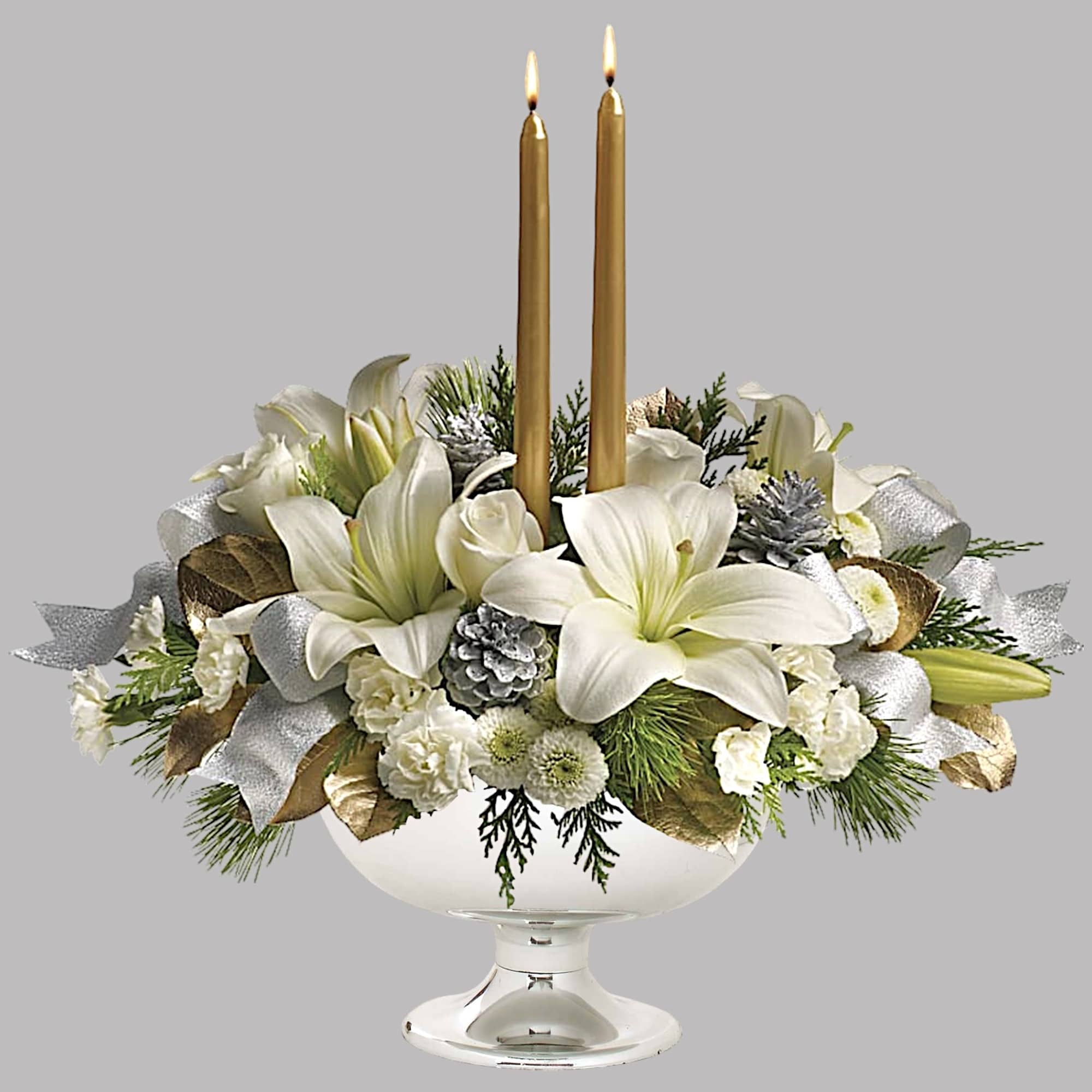 White lilies and candles arranged in a glass compote vase