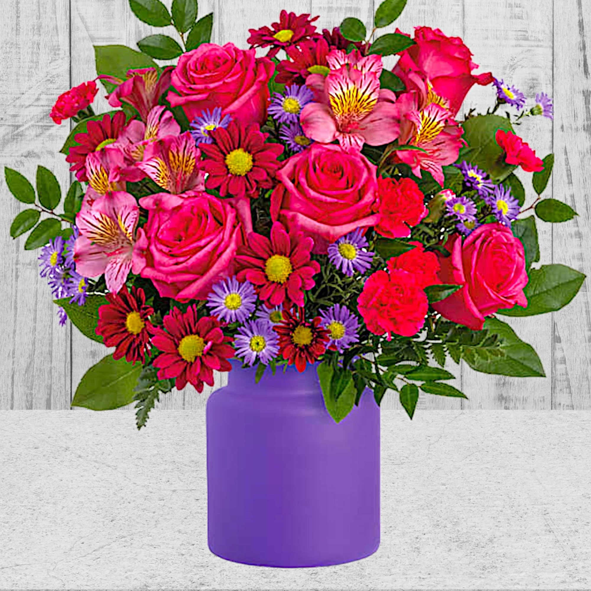 Bouquet of pink roses and mixed daisies in a purple vase