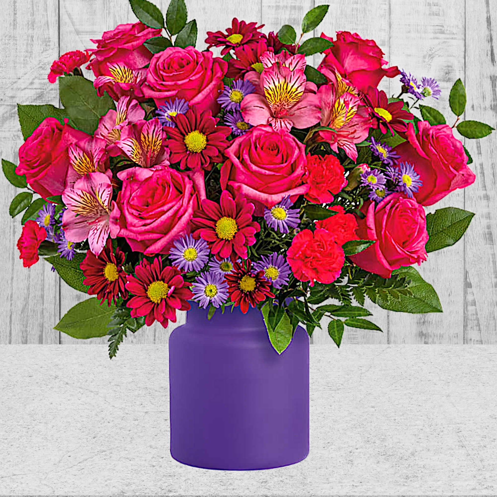 Pink mixed flower bouquet in a purple vase