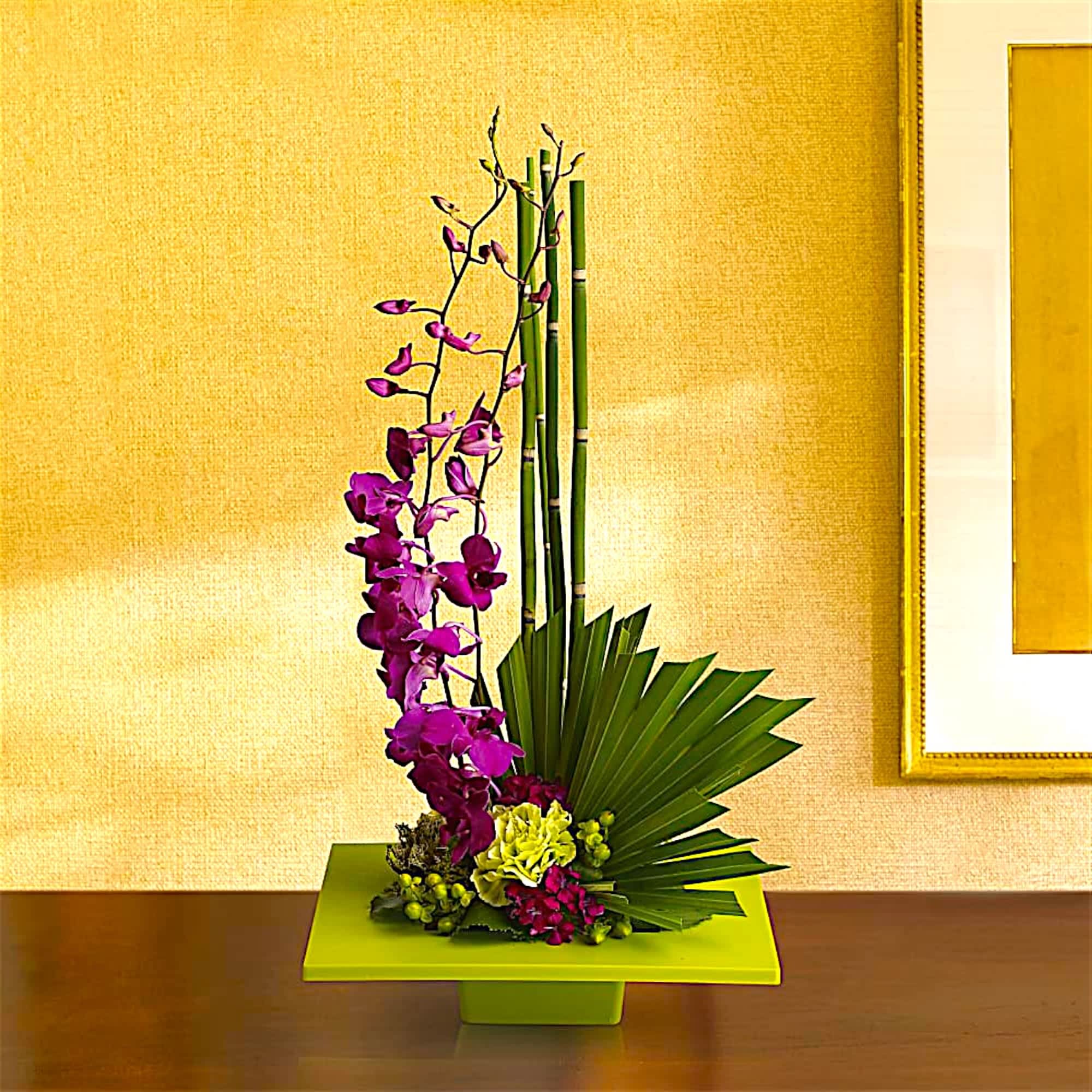 Purple orchid arrangement in a lime green vase with bamboo accents