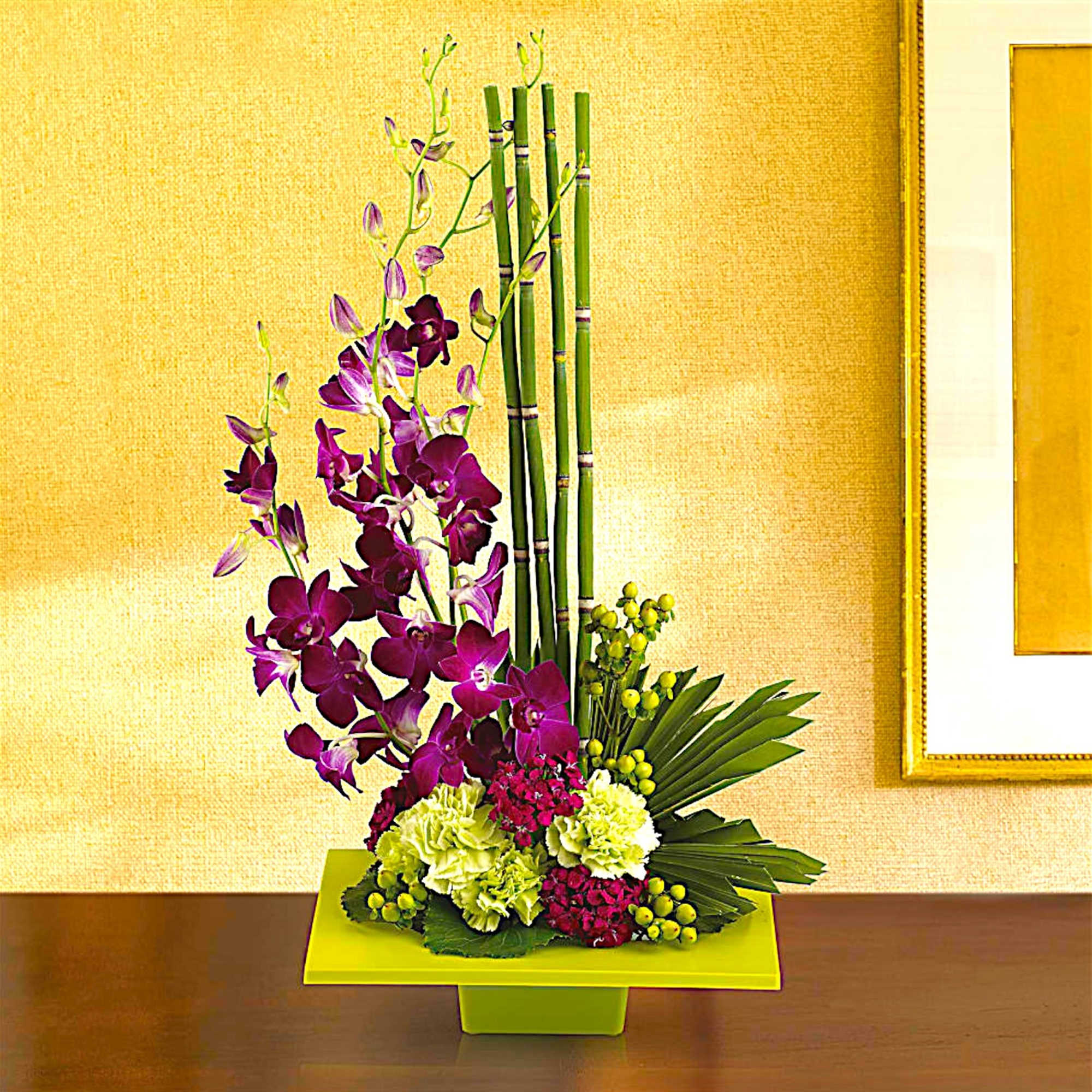 Purple orchids arranged with green bamboo in a lime vase