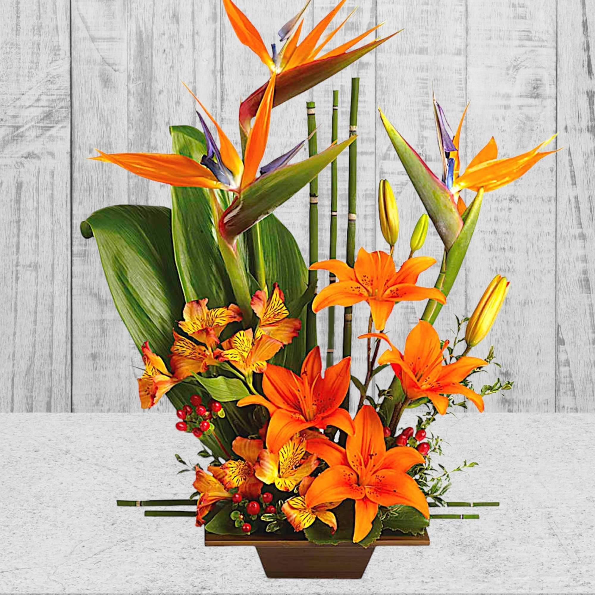 Orange lilies and bird of paradise in a rectangular vase
