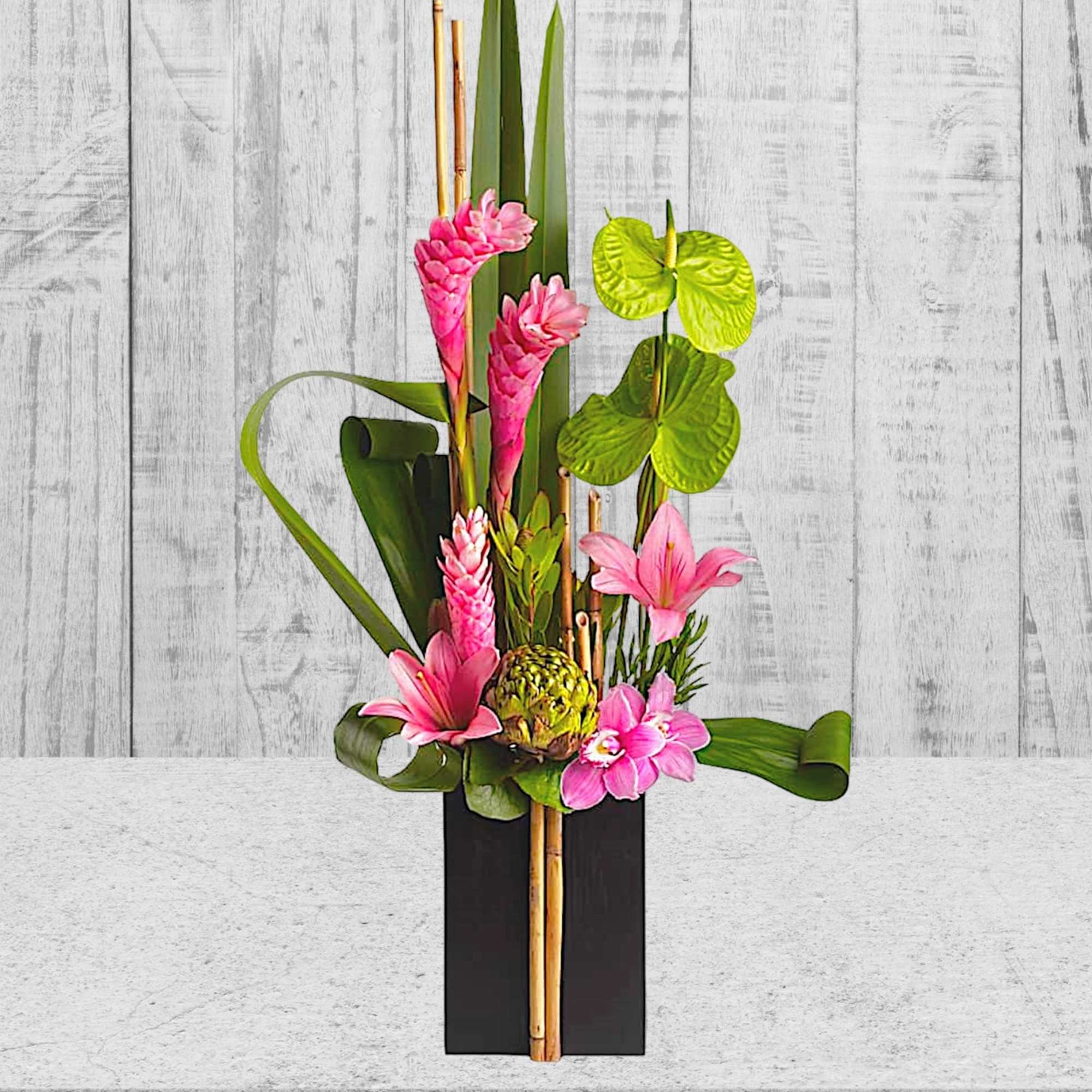 Tall tropical arrangement with pink flowers in a black rectangular vase