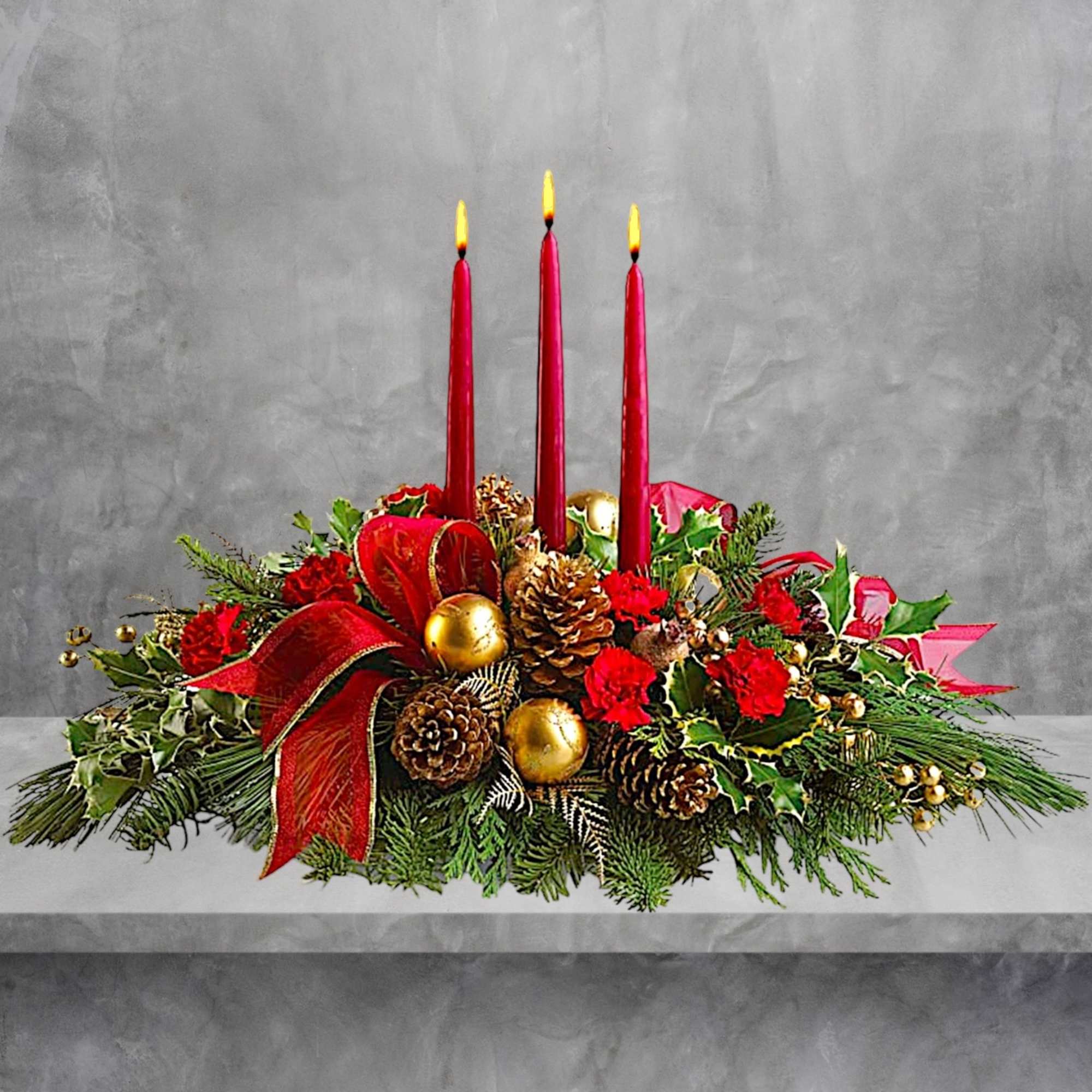 Holiday centerpiece with red candles, pinecones, and red ribbon