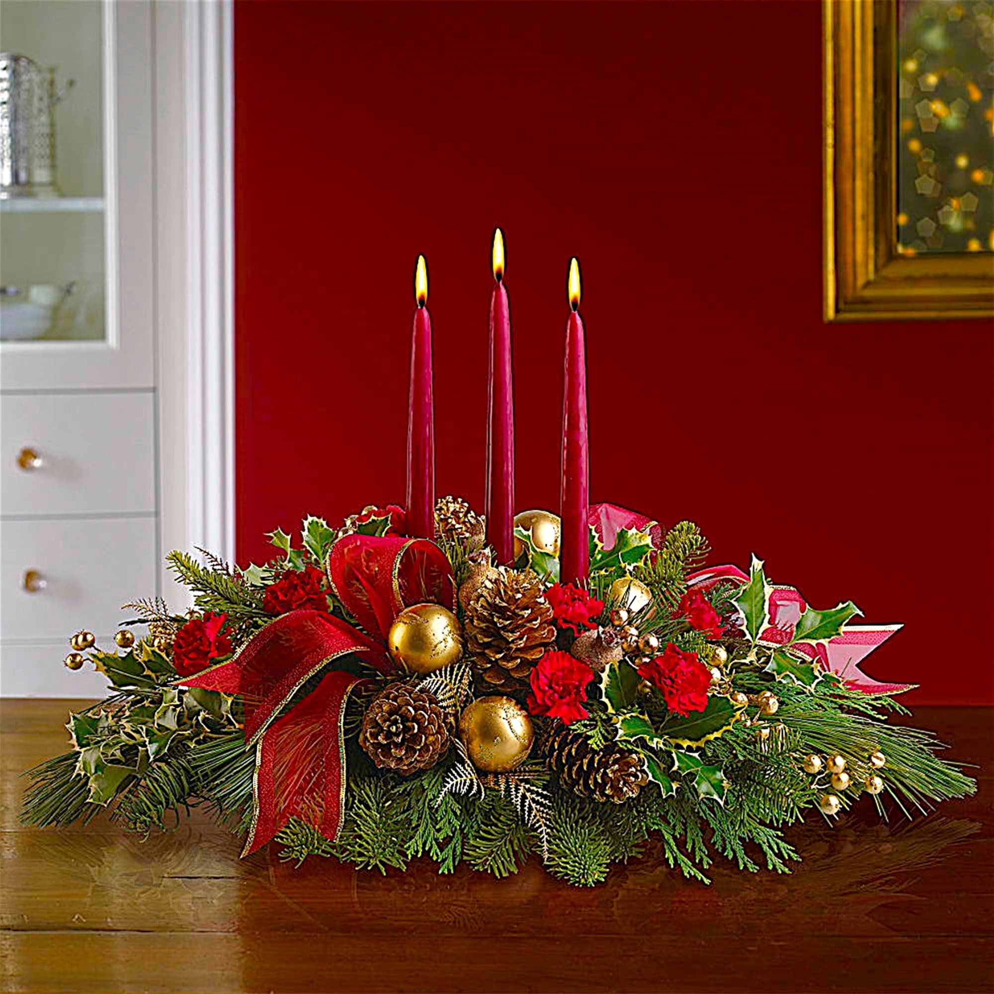 Holiday centerpiece with red candles, pinecones, and red flowers