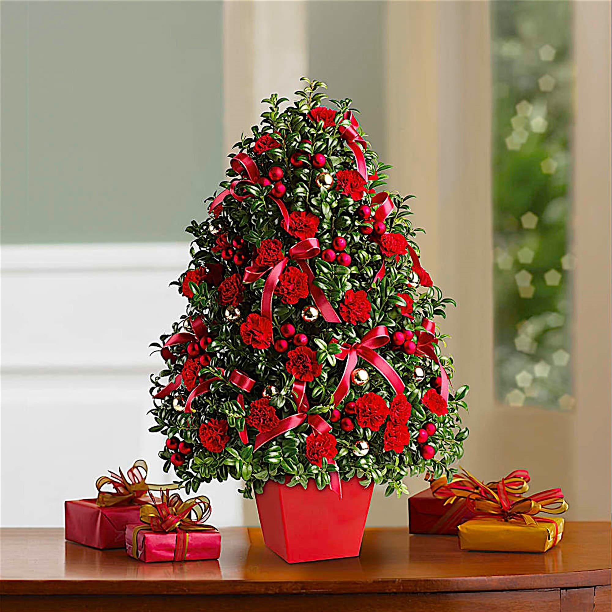 Christmas tree-shaped floral arrangement in a red pot with gift boxes
