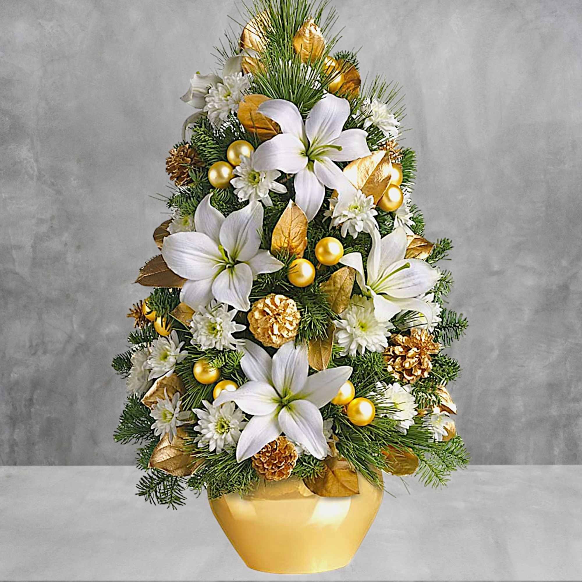 Christmas tree-shaped floral arrangement in a gold vase with white lilies and gold accents