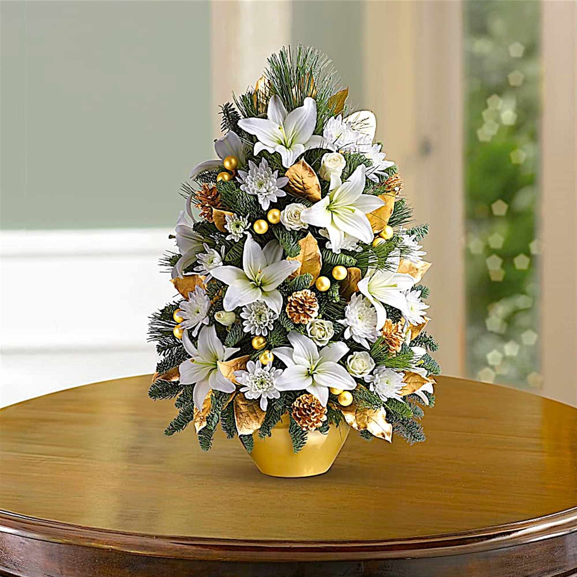 White lilies and small white blooms arranged in a gold pot