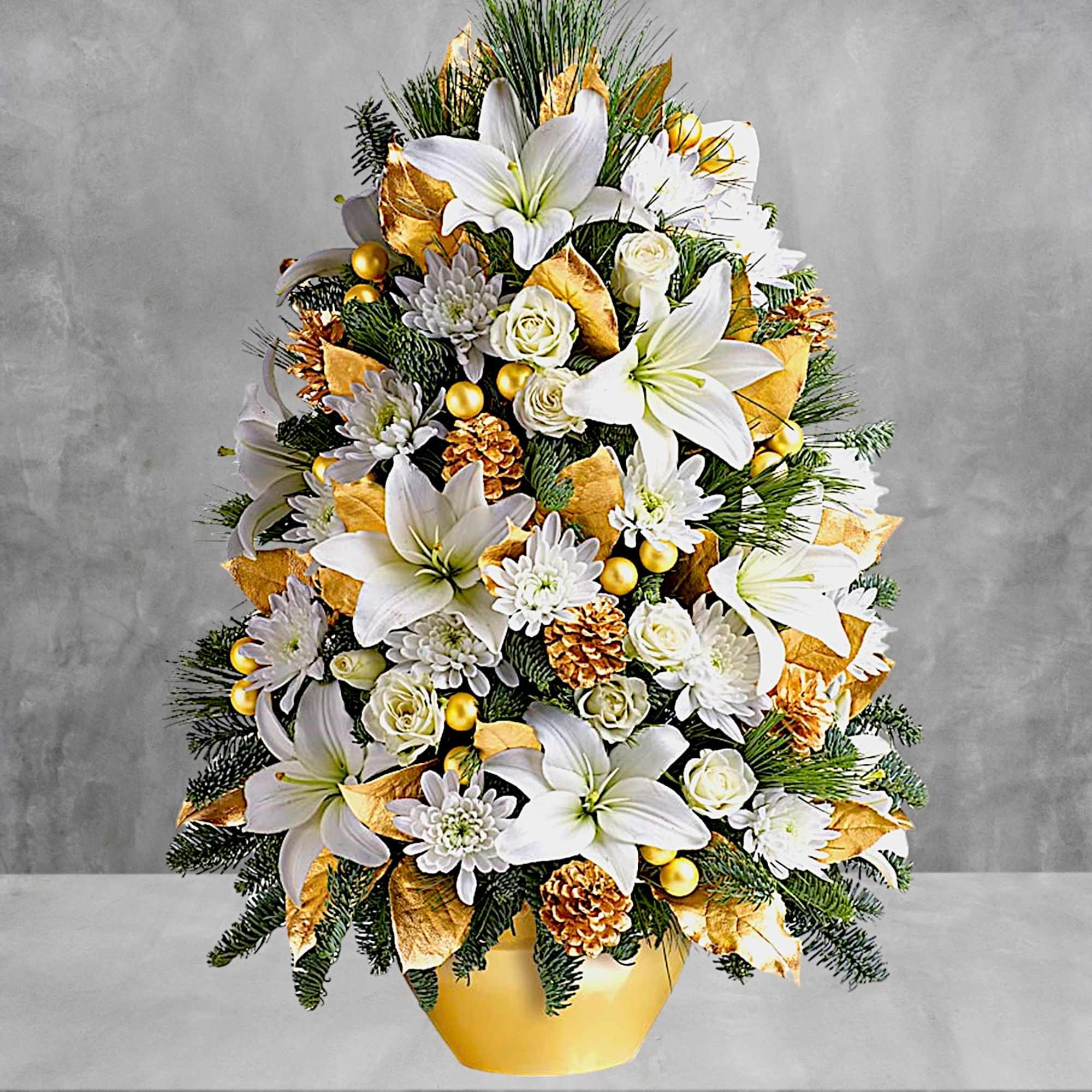 White lilies and roses arranged in a gold vase with pinecones and gold accents