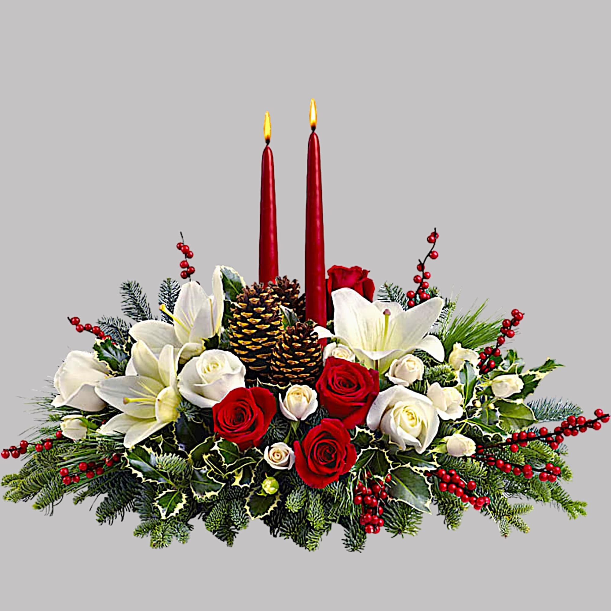 Holiday centerpiece with red and white flowers, pinecones, and two red candles