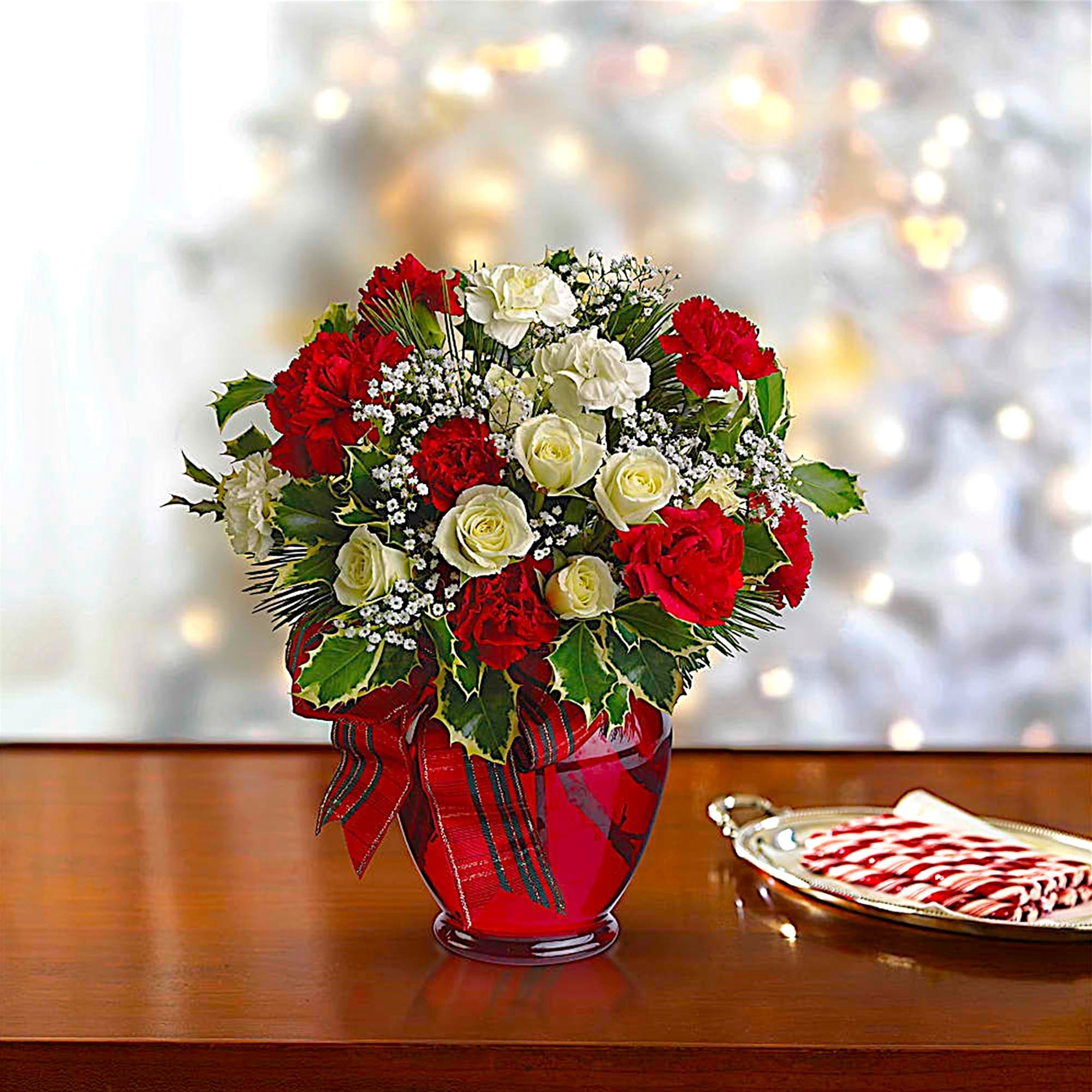 Red and white rose bouquet in a red vase with a plaid ribbon