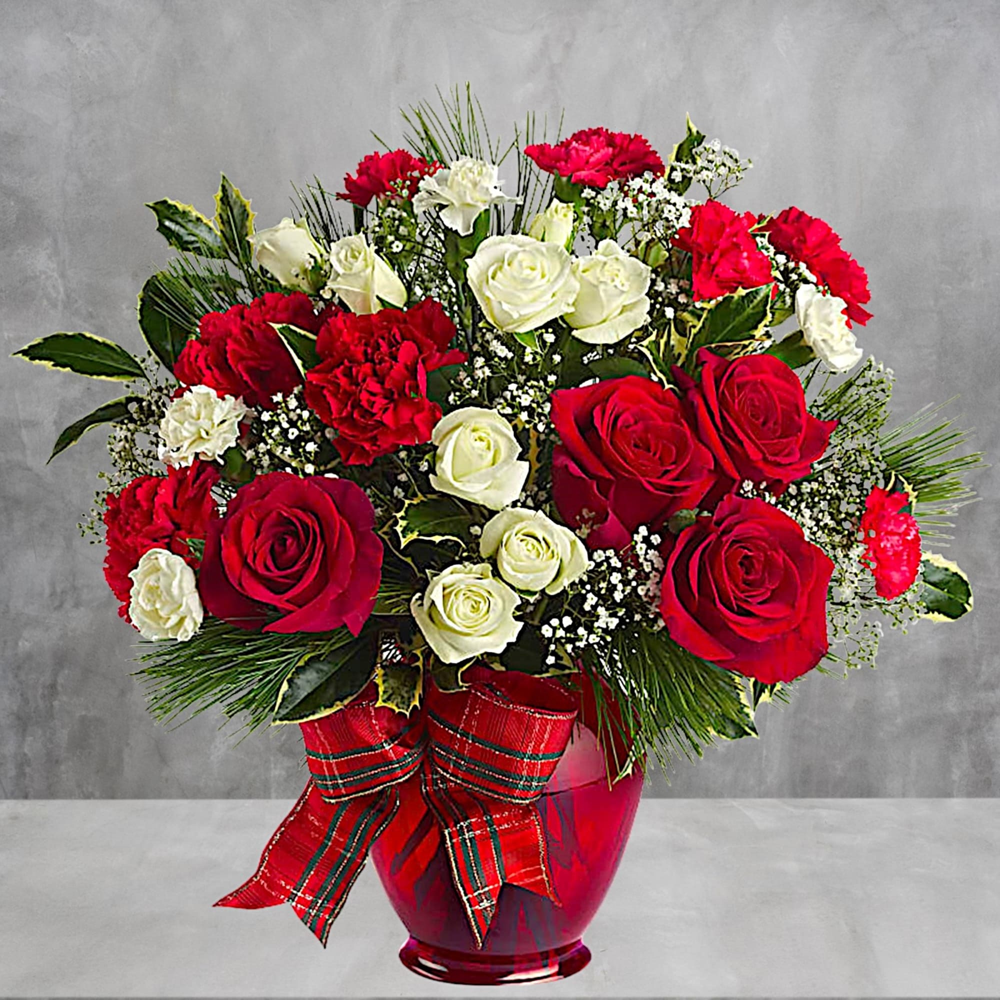 Red and white roses with carnations in a red vase and plaid ribbon