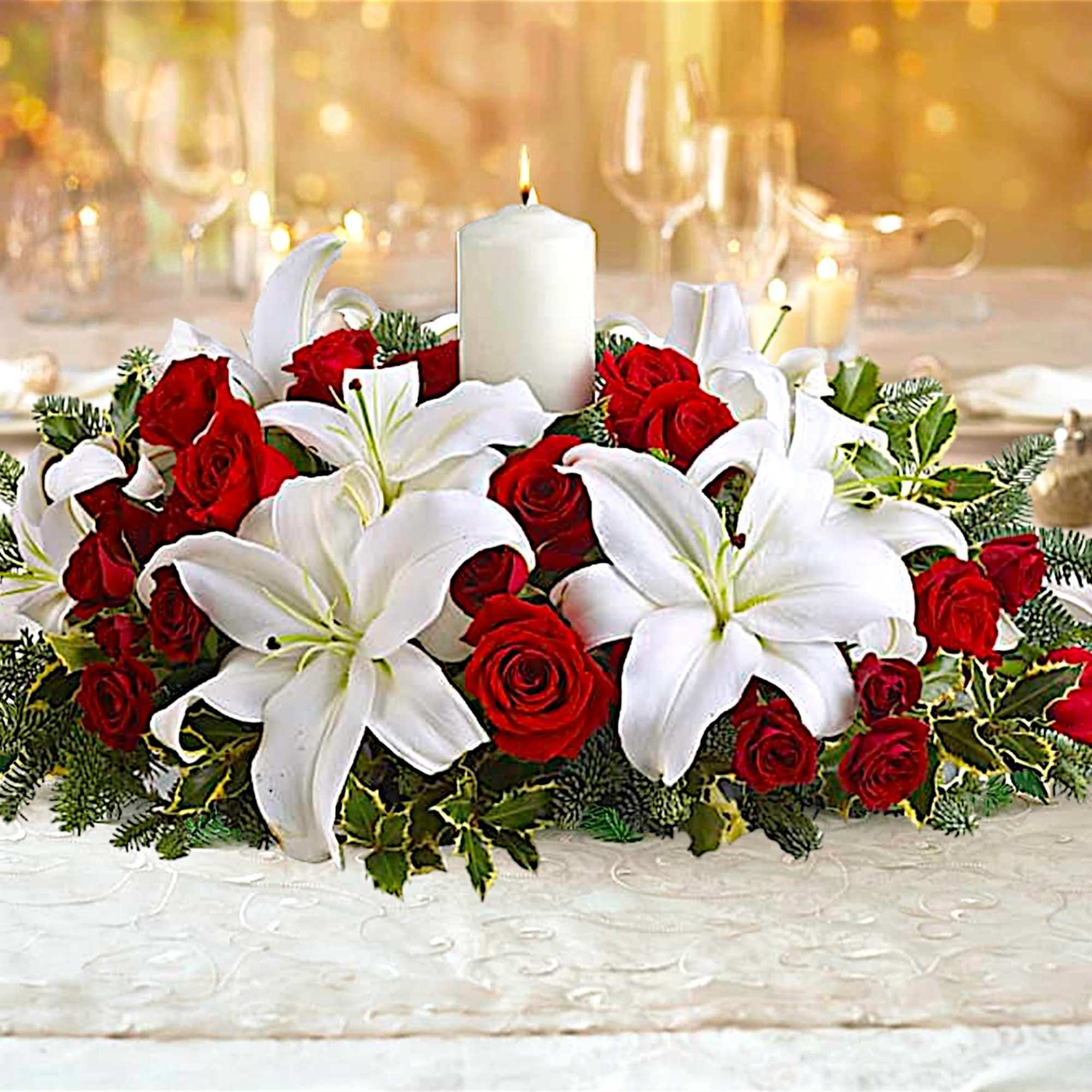 Red roses and white lilies arranged around a white pillar candle