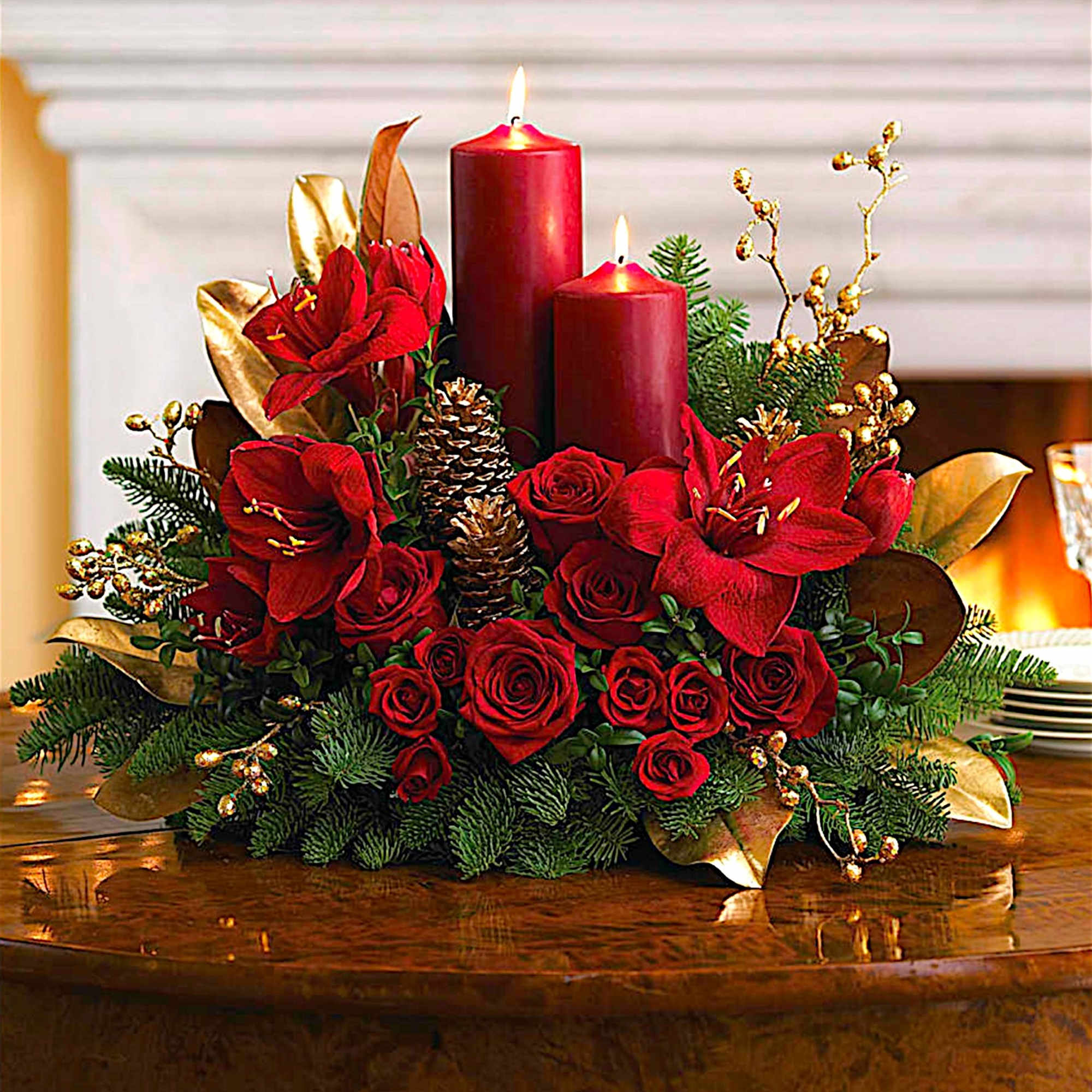 Red floral centerpiece with two lit candles and pinecones